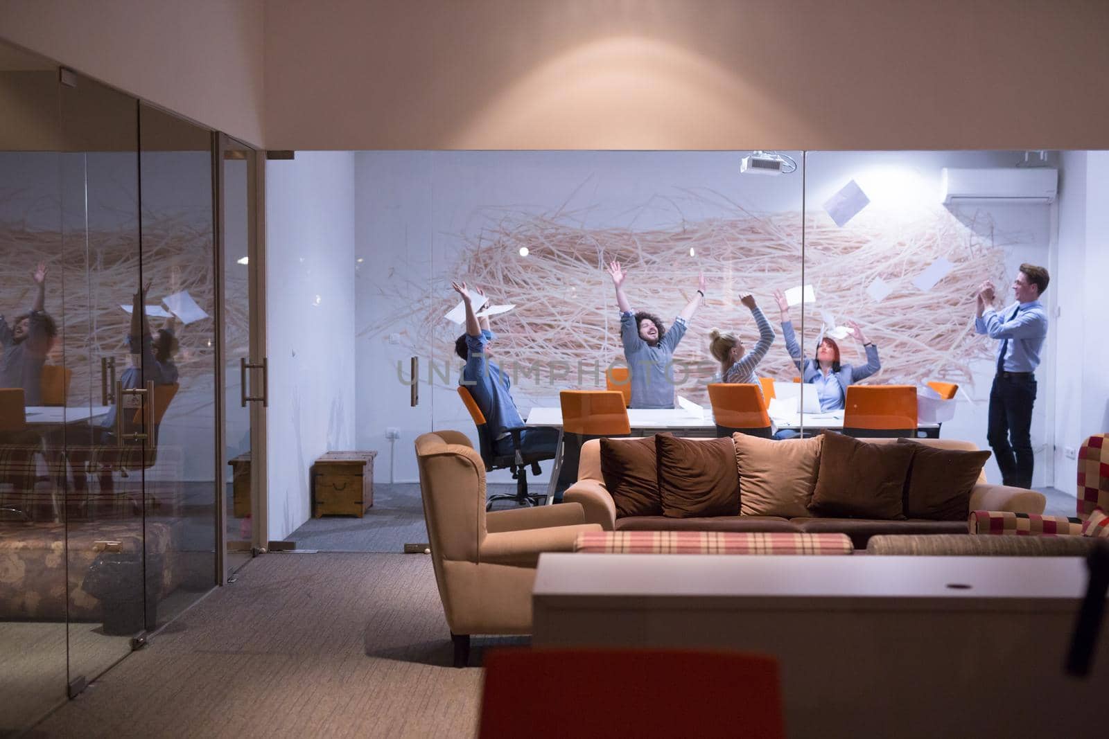 Group of young business people throwing documents and looking happy while celebrating success at their working places in night office