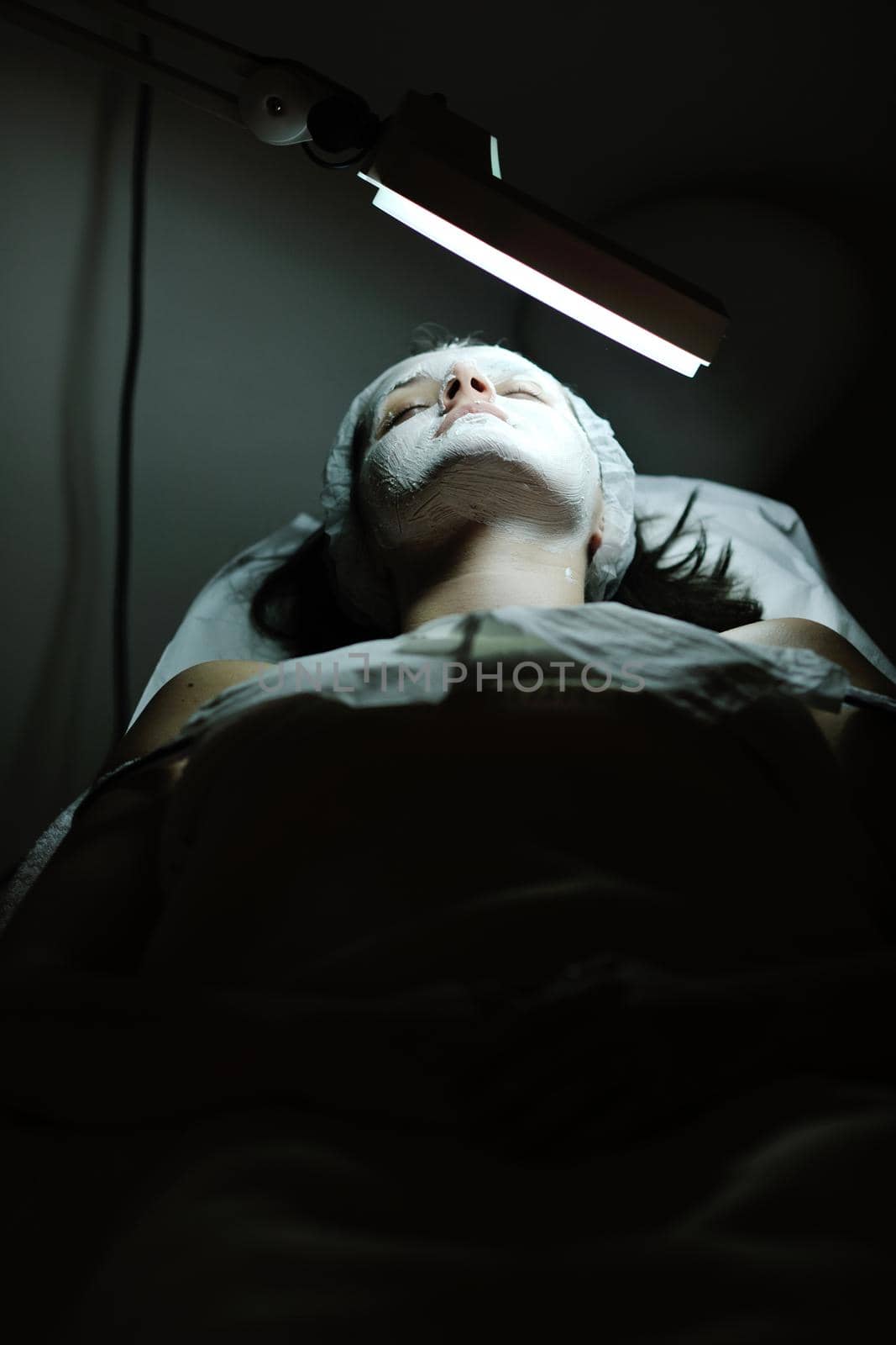 woman with facial mask in cosmetic studio by dotshock