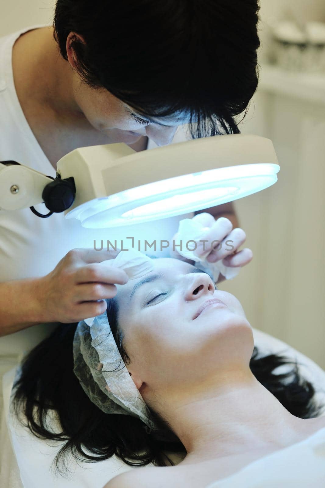 Young beautiful woman receiving cosmetic facial mask in spa beauty salon and relax