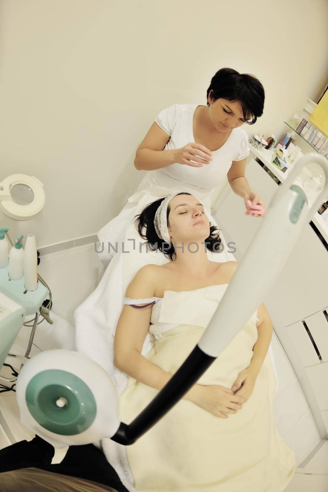 Young beautiful woman receiving cosmetic facial mask in spa beauty salon and relax