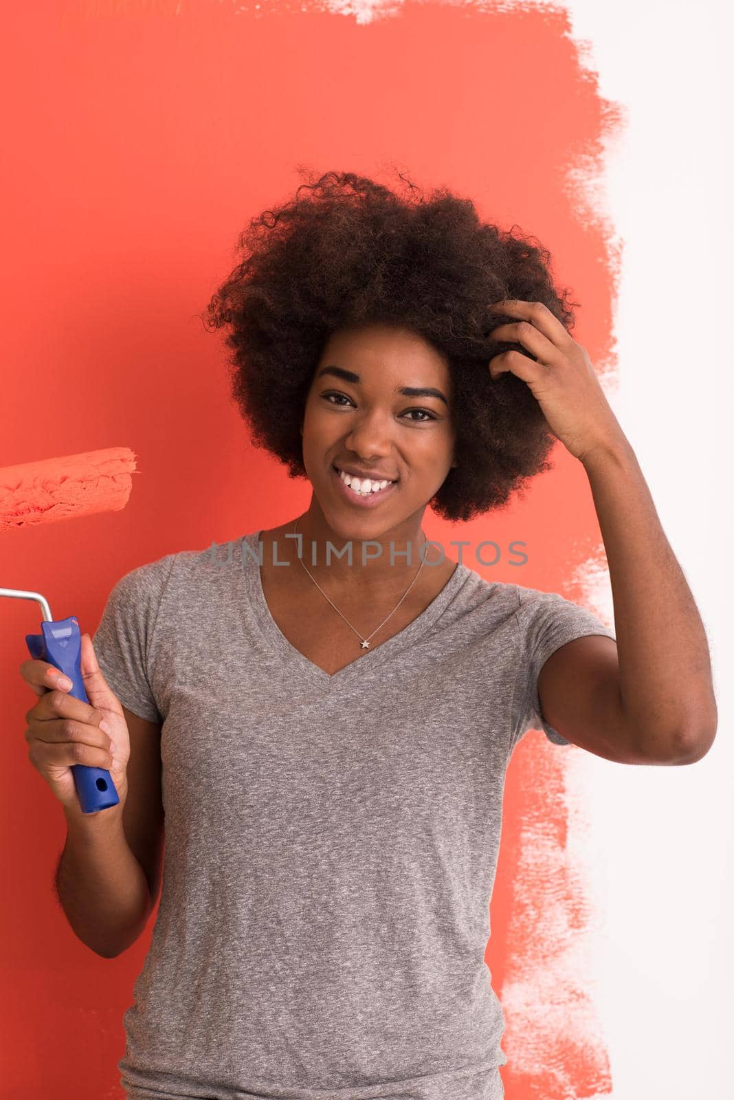 portrait of a young beautiful African American woman painting wall in her new apartment