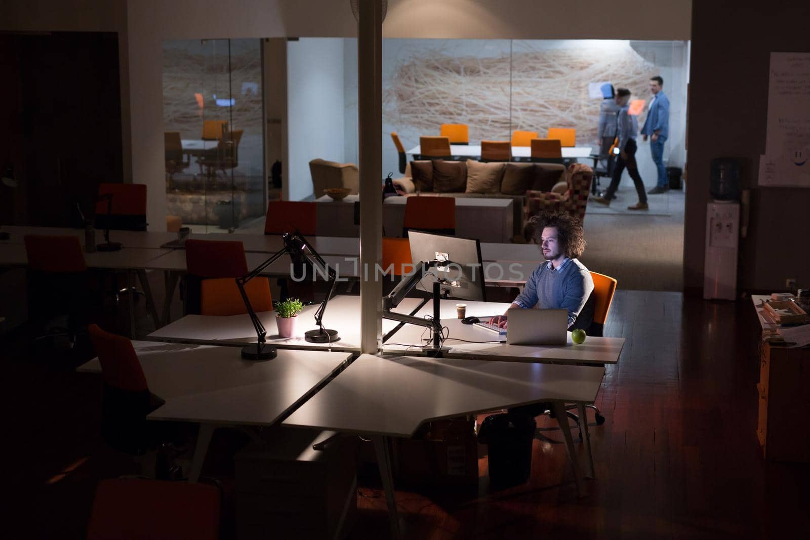 Young man working on computer at night in dark office. The designer works in the later time.