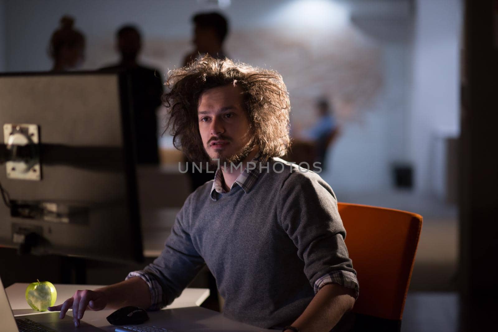 Young man working on computer at night in dark office. The designer works in the later time.