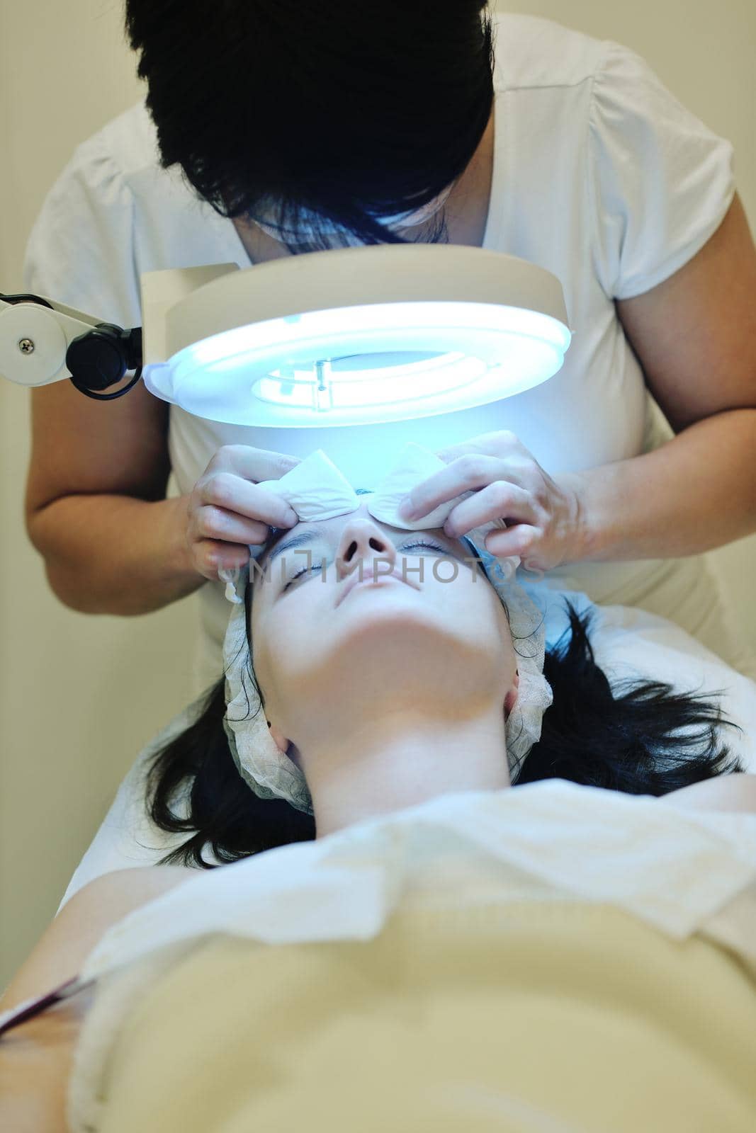 Young beautiful woman receiving cosmetic facial mask in spa beauty salon and relax