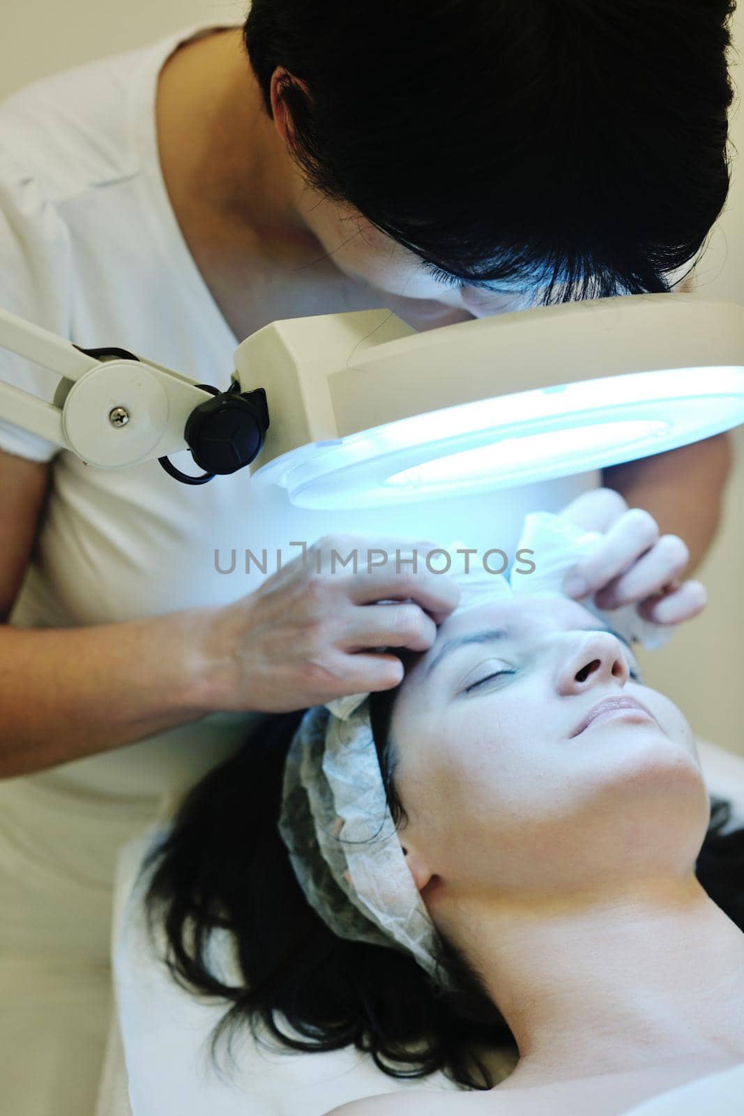 Young beautiful woman receiving cosmetic facial mask in spa beauty salon and relax