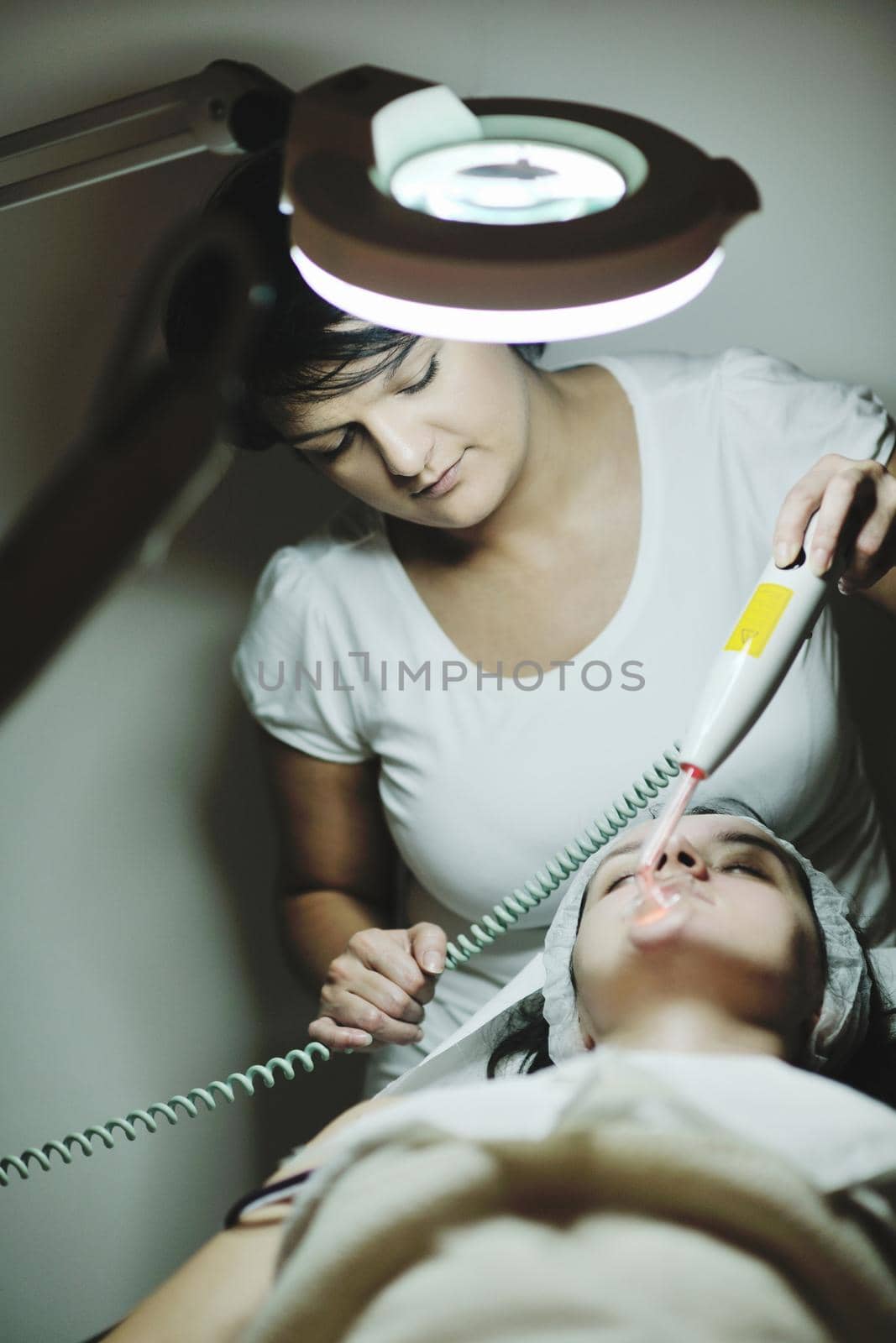 Young beautiful woman receiving cosmetic facial mask in spa beauty salon and relax