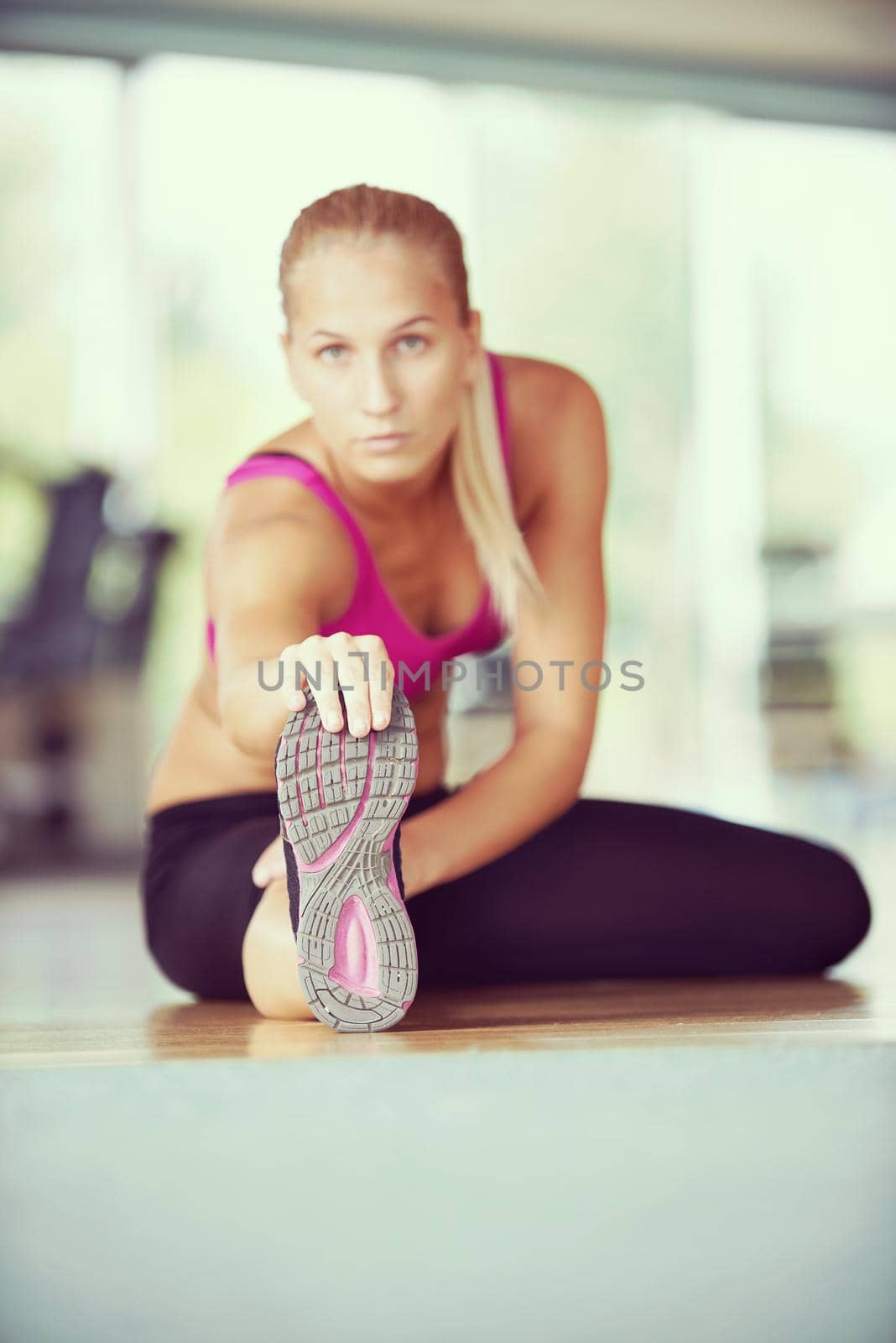 woman stretching and warming up for her training at a gym by dotshock