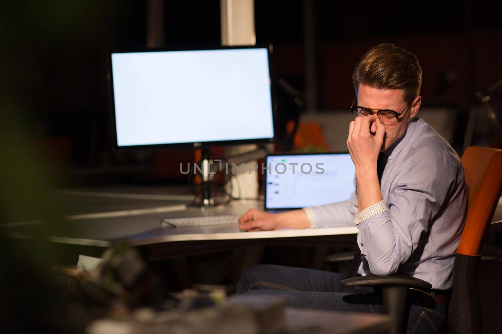 Young man working on computer at night in dark office. The designer works in the later time.