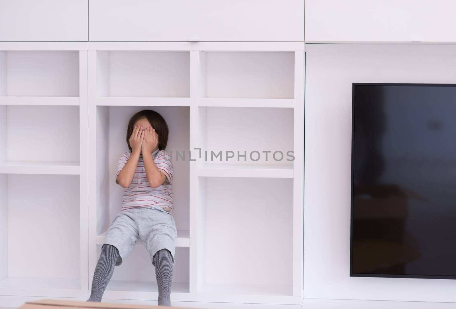 happy young boy having fun while posing on a shelf in a new modern home