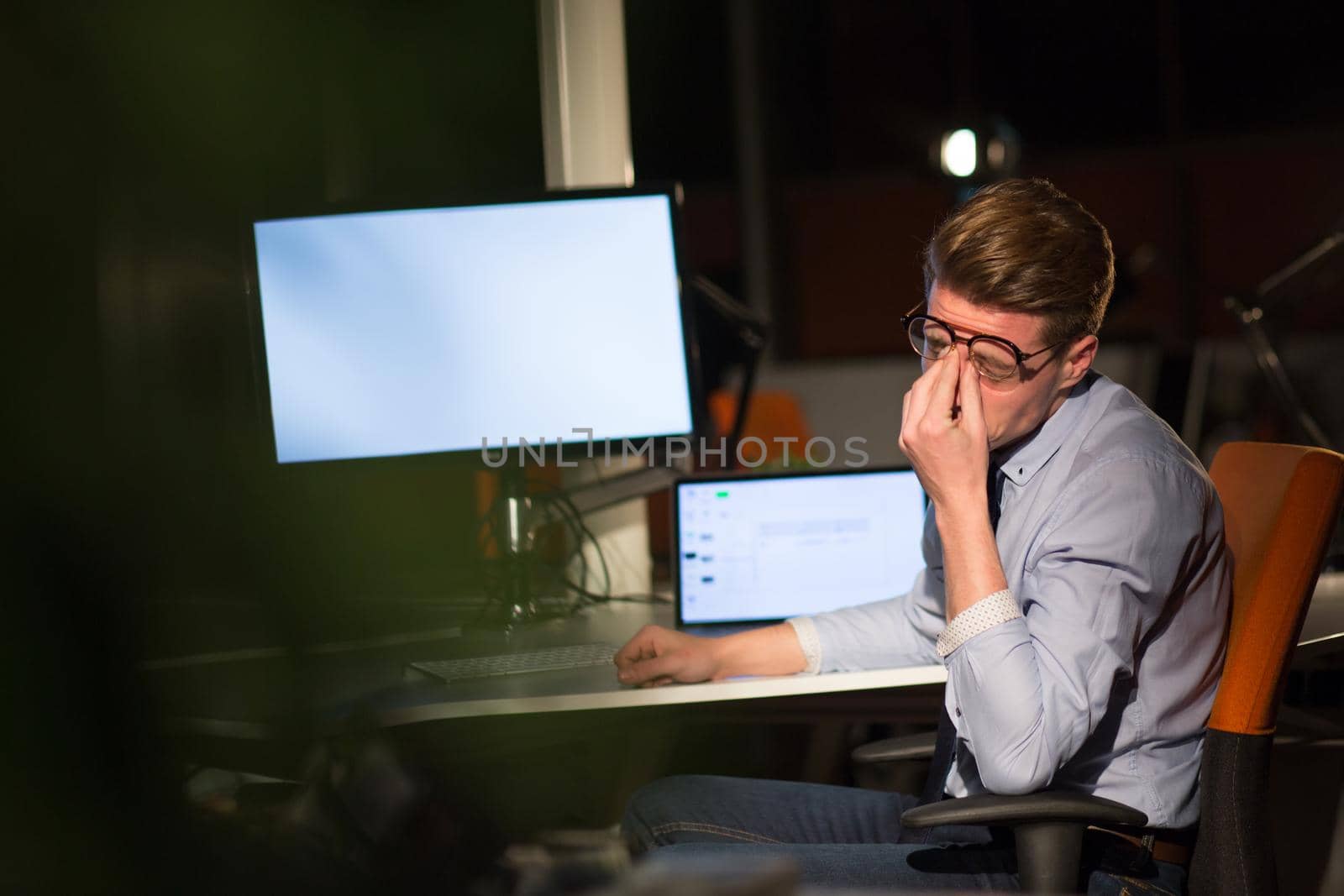 man working on computer in dark office by dotshock