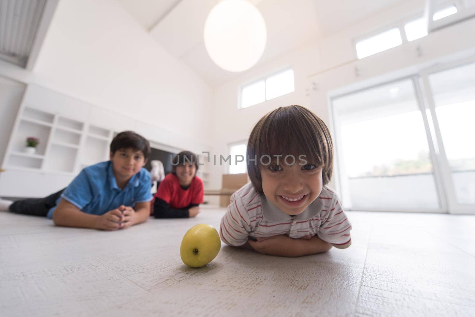 happy young boys having fun with an apple on the floor in a new modern home