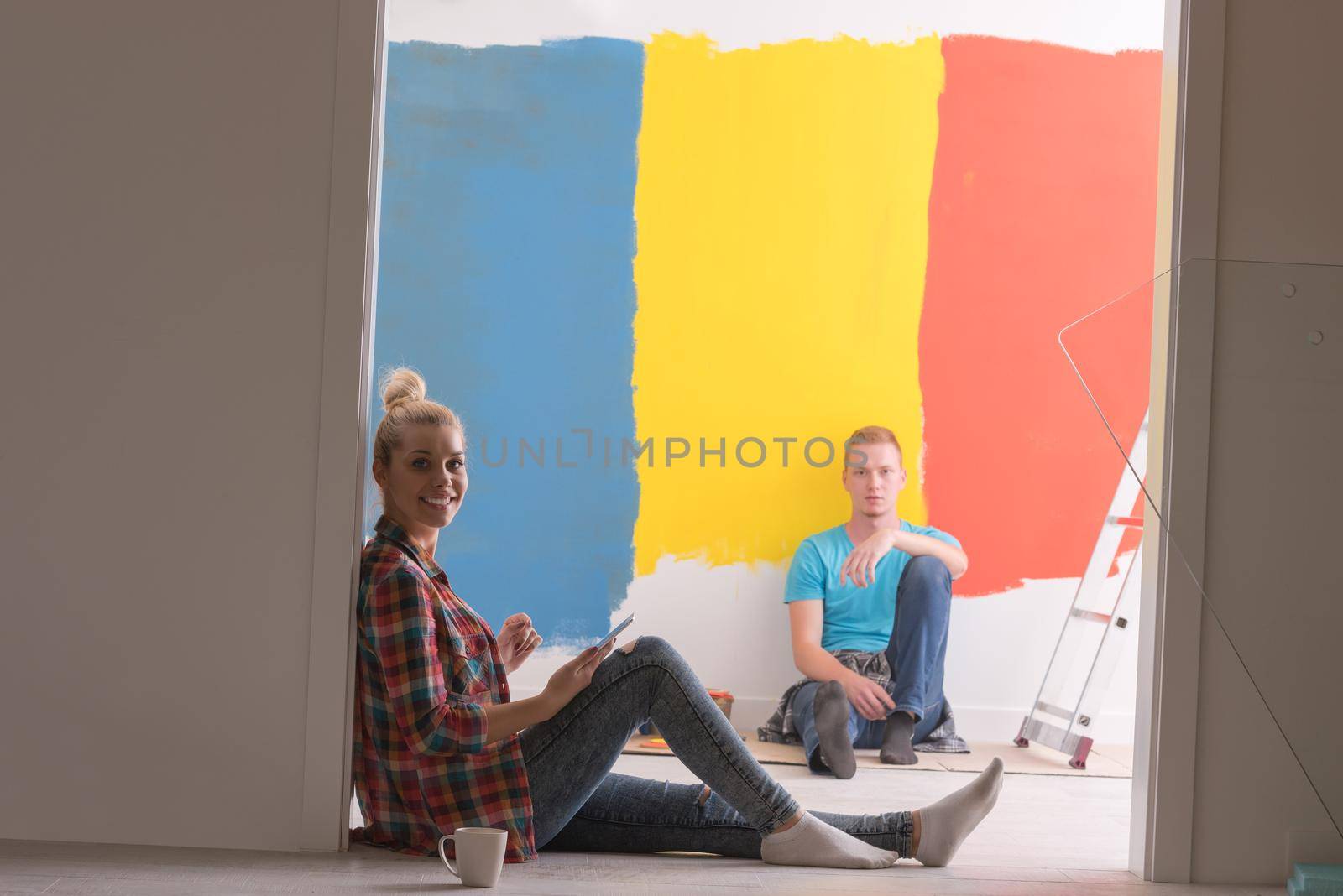 Happy young couple relaxing after painting a room in their new house on the floor