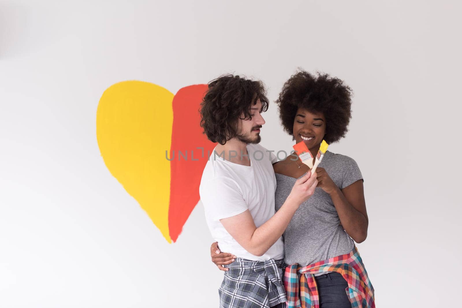 Portrait of loving multiethnict couple with painted heart on wall