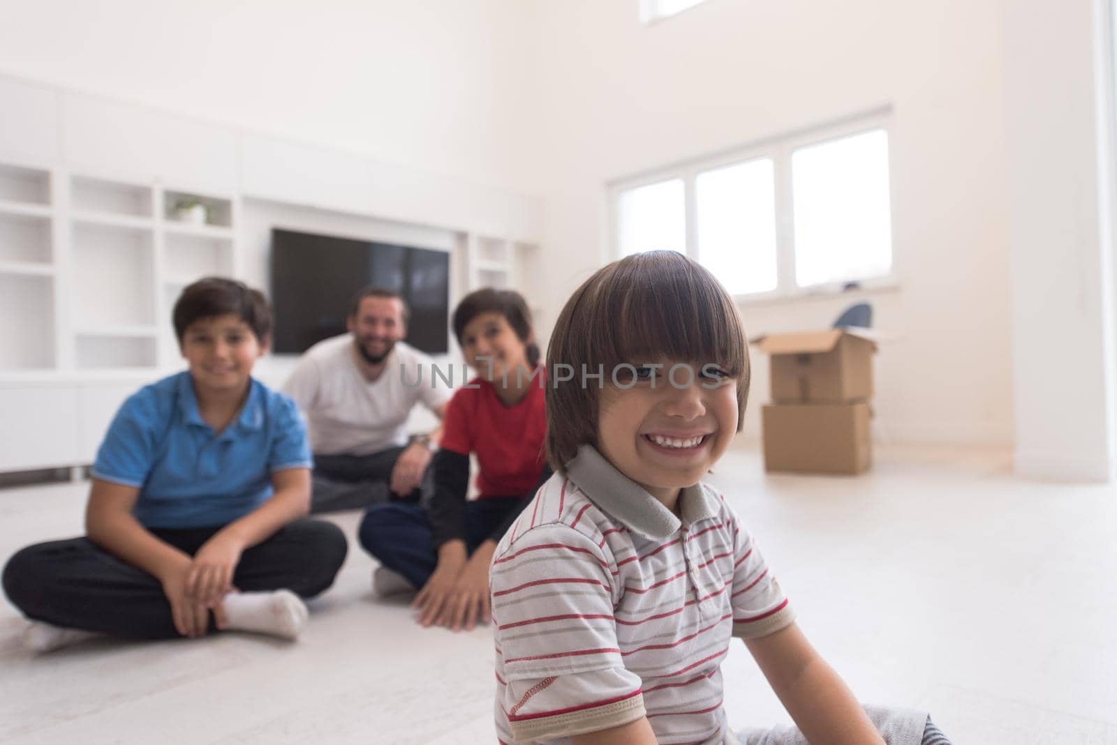 portrait of happy young boys with their dad sitting on the floor in a new modern home