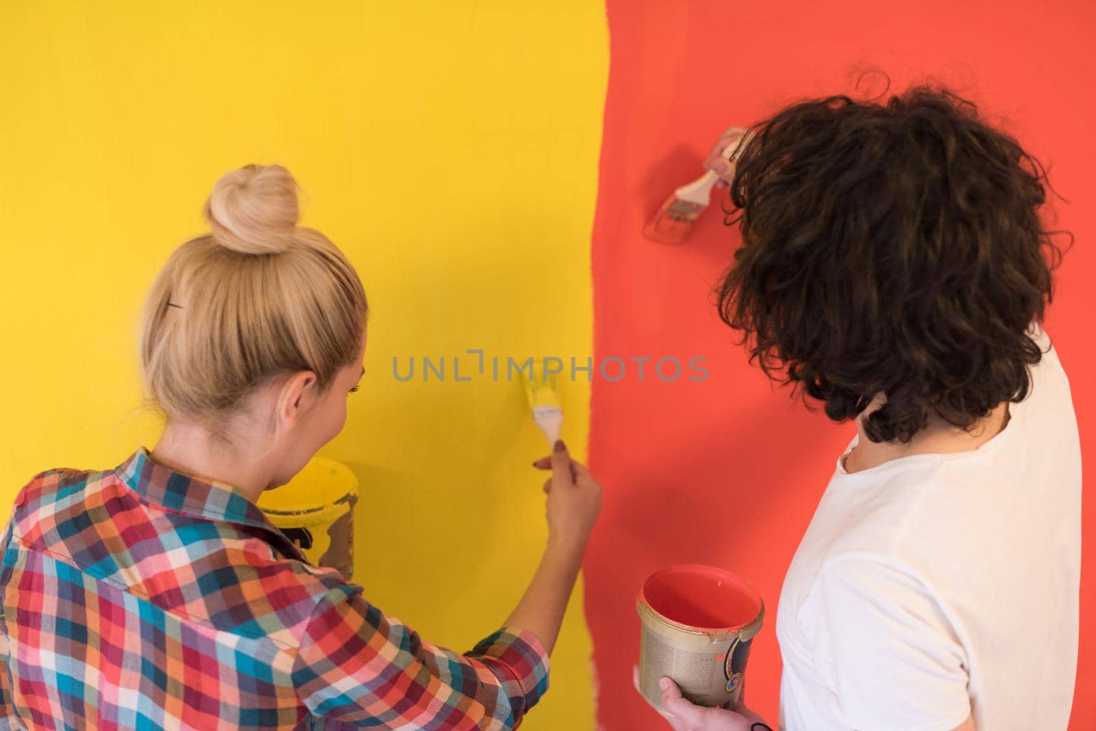 happy smiling young couple painting interior wall of new house