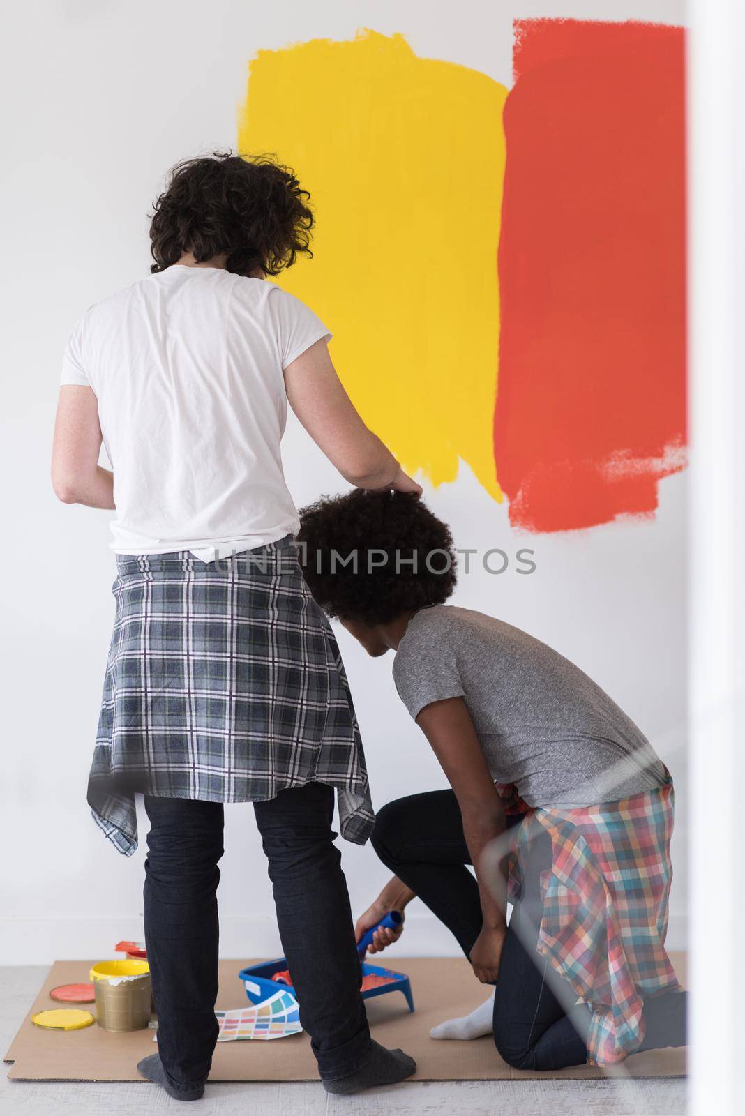 multiethnic couple painting interior wall by dotshock