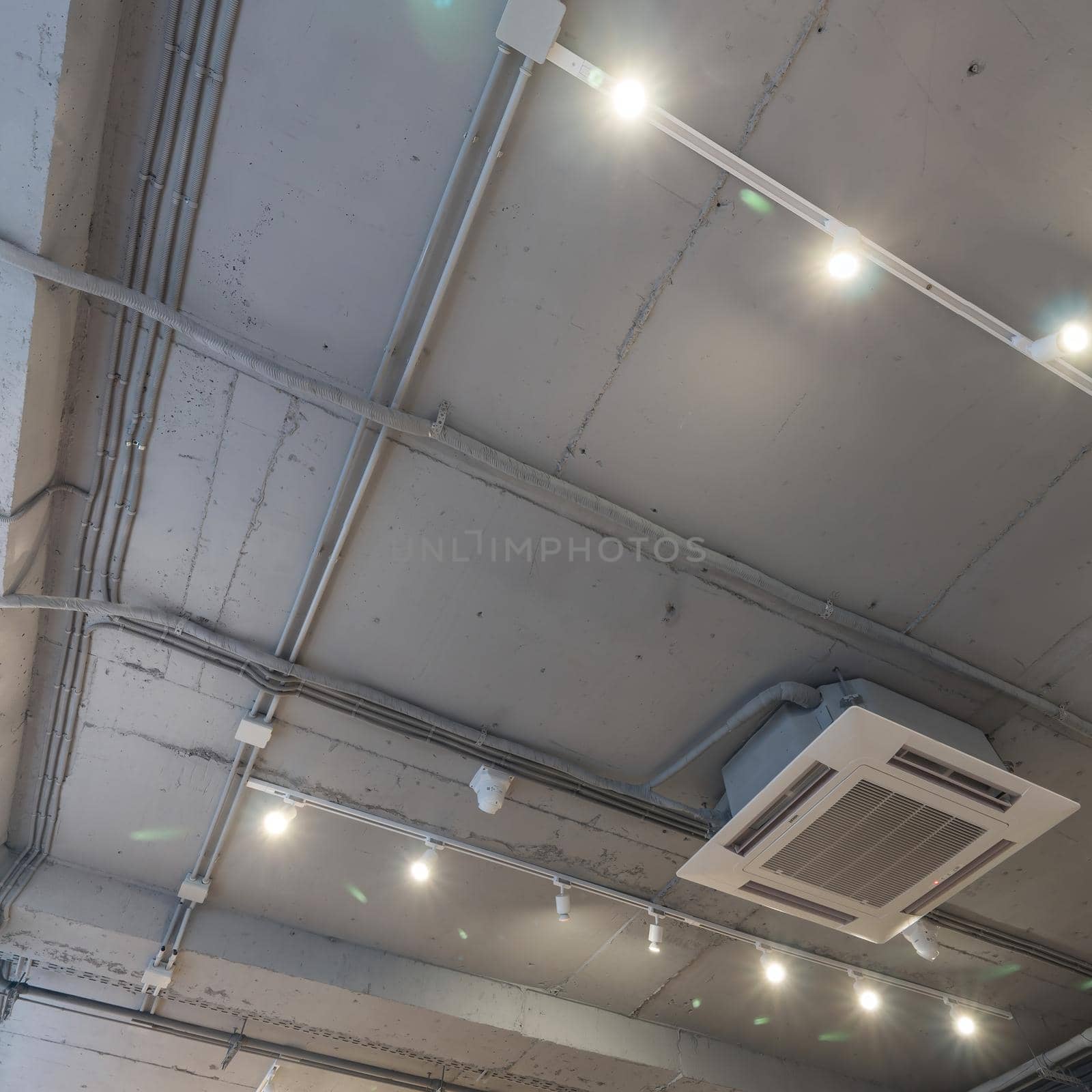 Abstract loft interior of concrete grey ceiling with air ventilation and security camera. Interior architecture and ceiling design of industrial loft building decorated with modern lamps by panophotograph