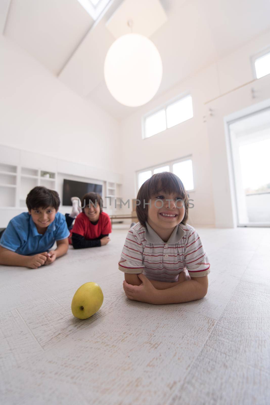 happy young boys having fun with an apple on the floor in a new modern home