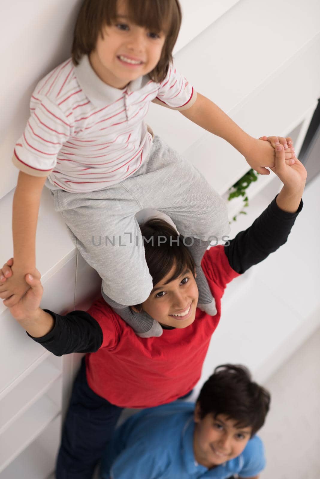 happy young boys having fun and posing line up piggyback in new modern home top view