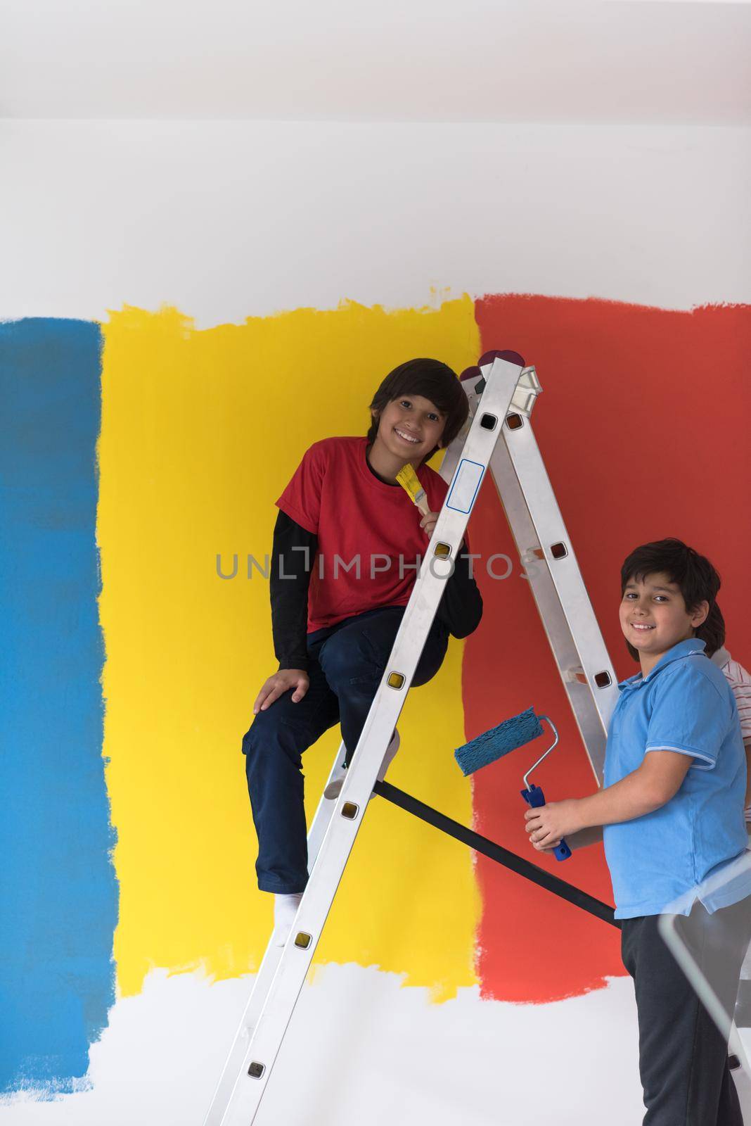 a group of young boys helps to paint a wall in new home