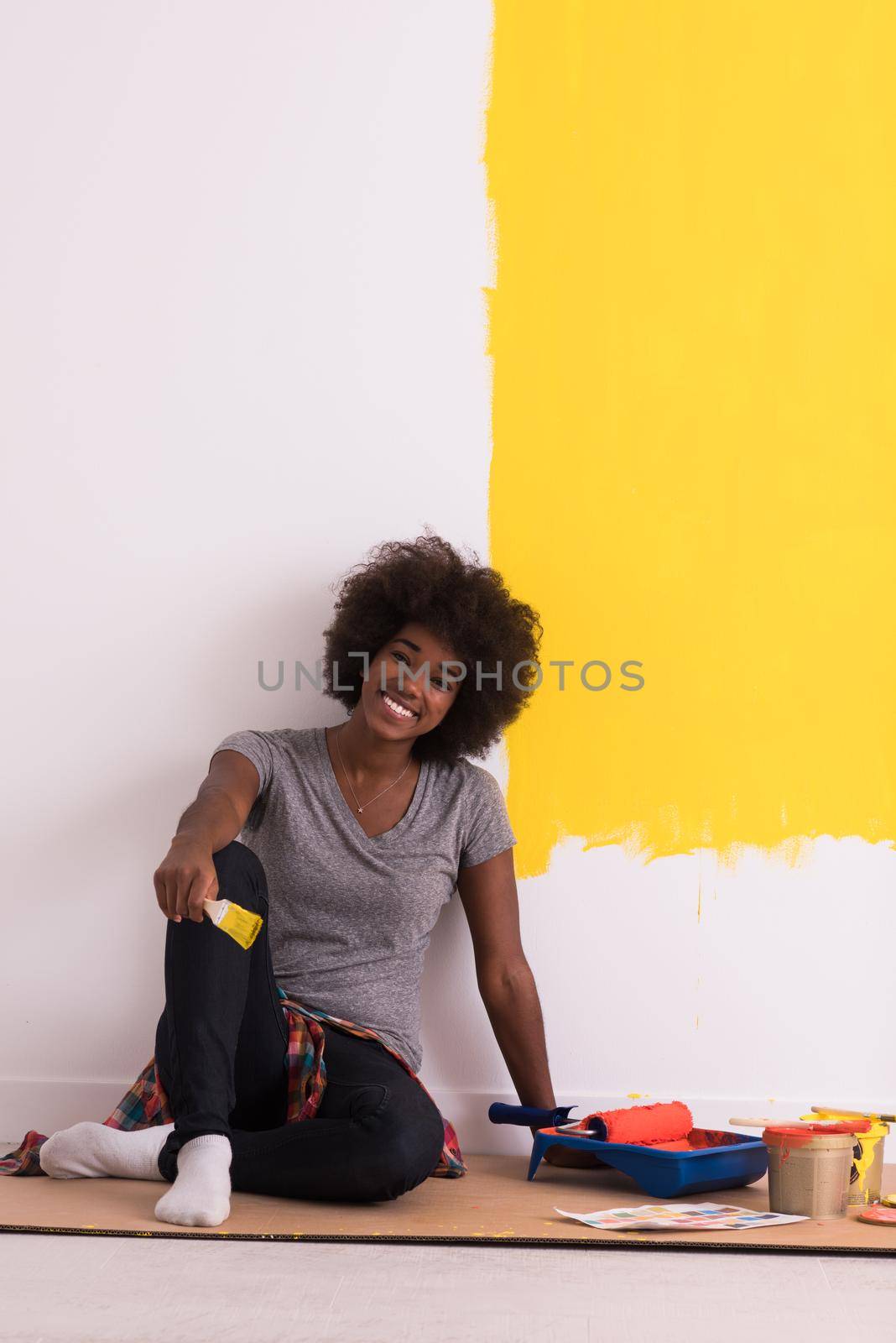 Portrait of a beautiful african american female painter sitting on floor near wall after painting.