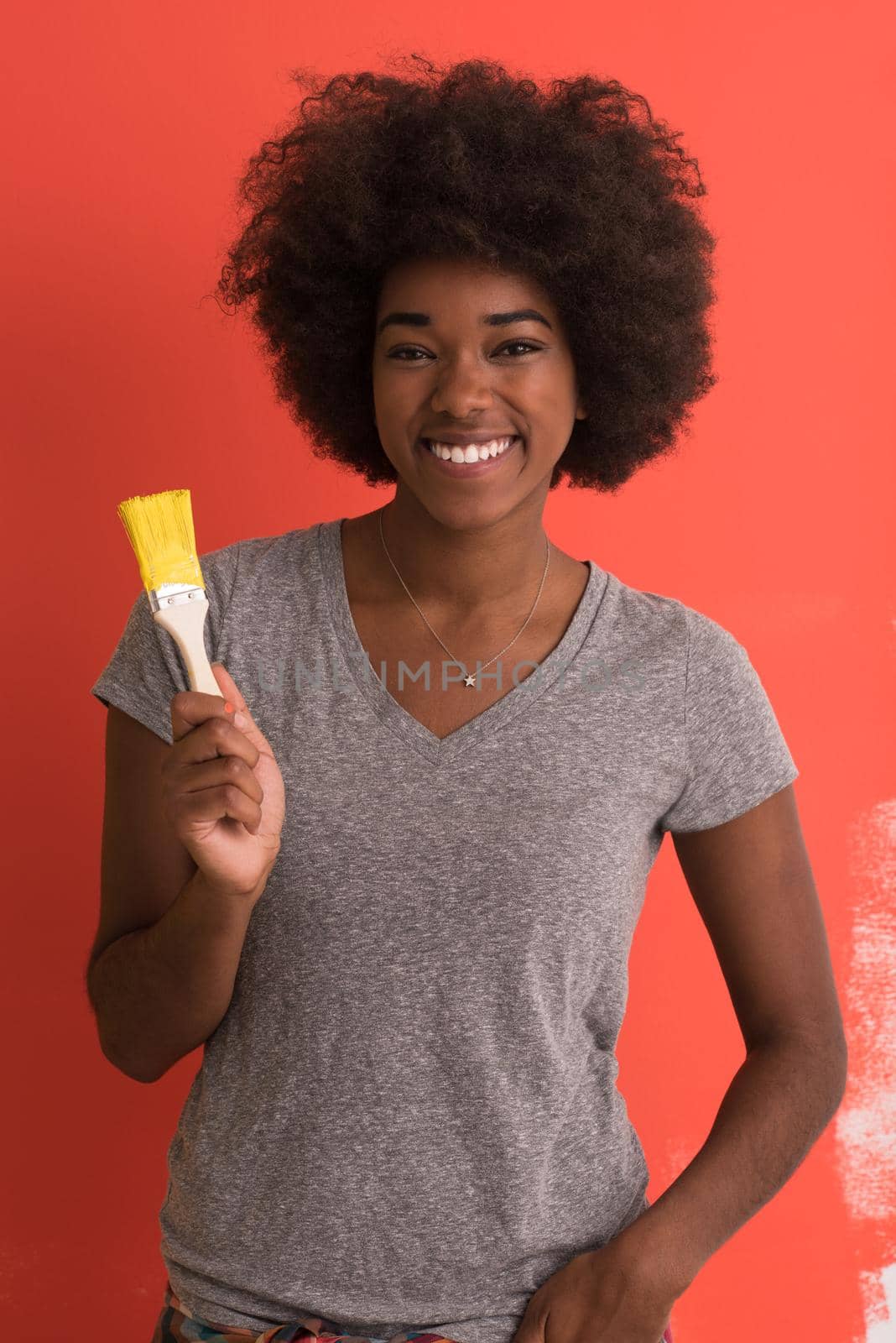 portrait of a young beautiful African American woman painting wall in her new apartment