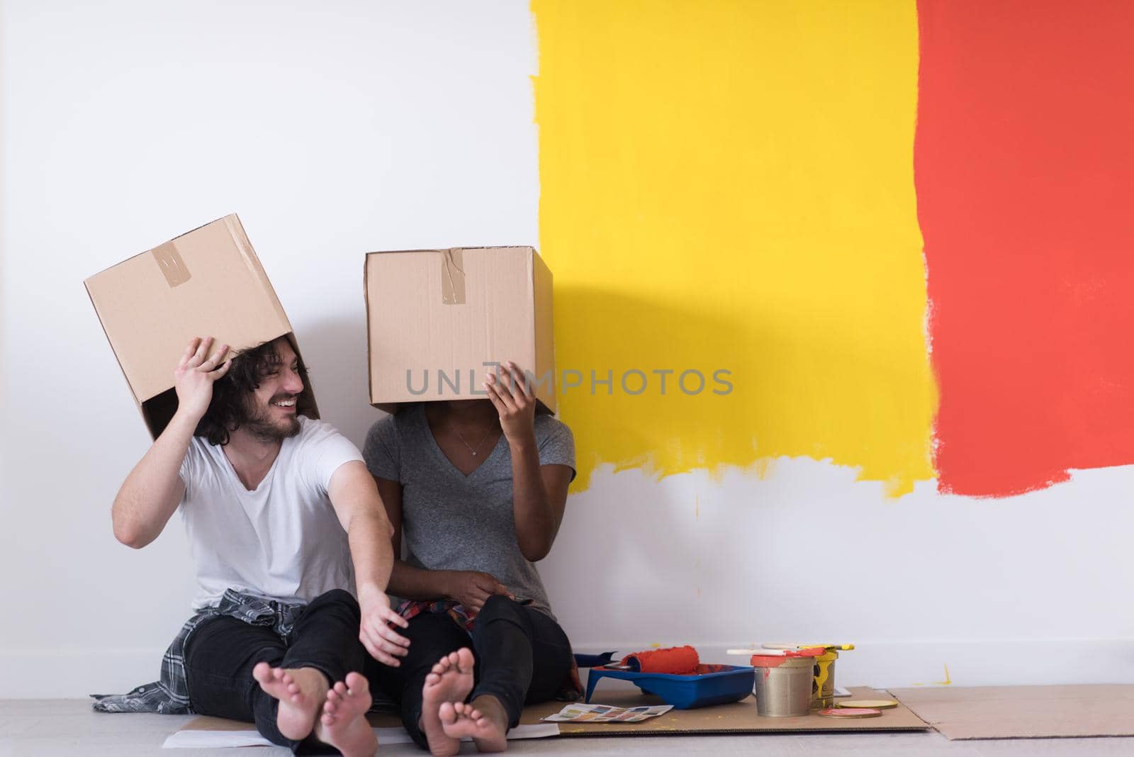 young multiethnic couple playing with cardboard boxes by dotshock