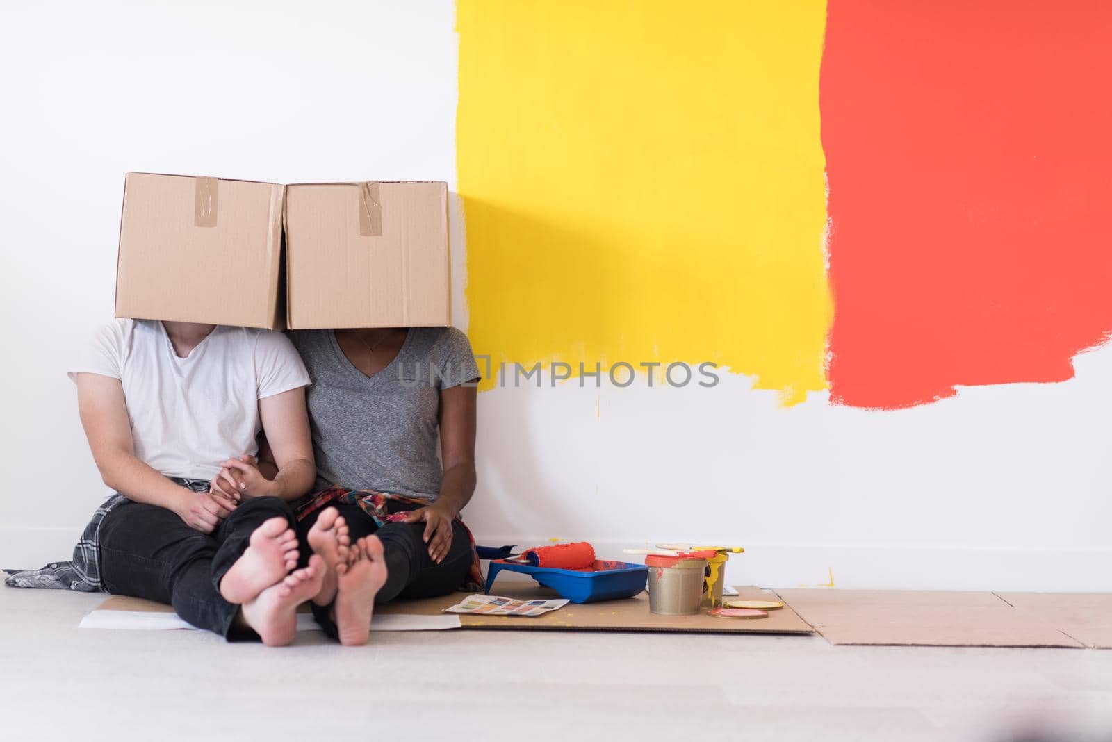 young multiethnic couple playing with cardboard boxes by dotshock