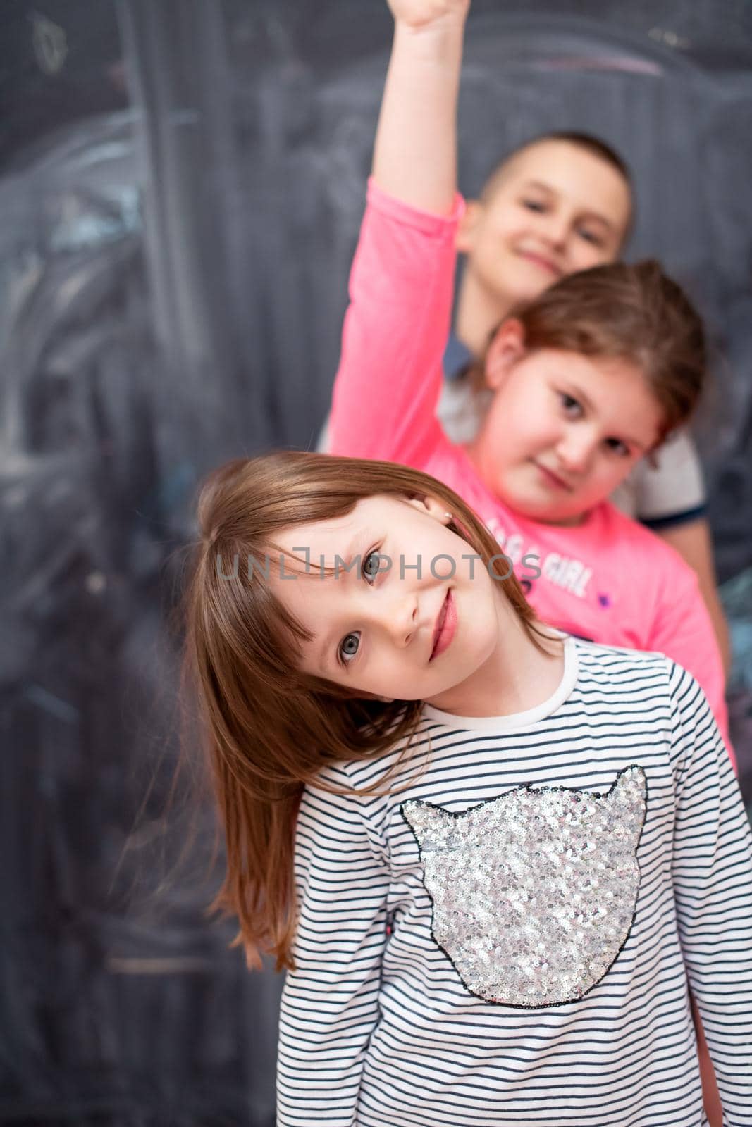 group portrait of happy childrens standing one behind the other while having fun in front of black chalkboard