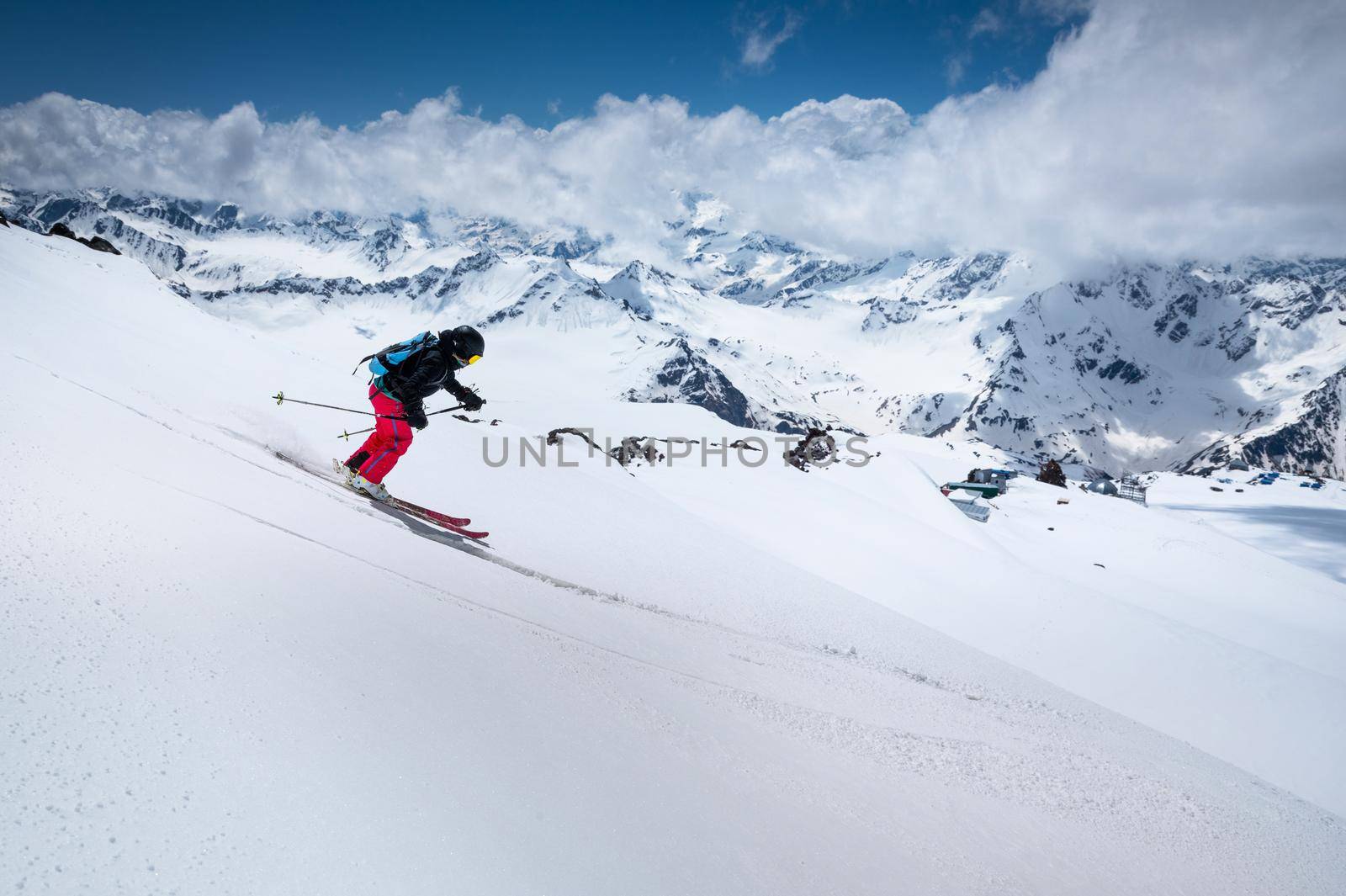 Woman Skier skiing downhill in high mountains against mountains and clouds. by yanik88
