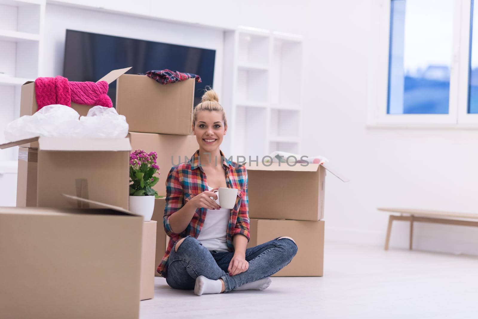 people, moving new place and repair concept   happy beautiful  young woman with many cardboard boxes sitting on floor with Cup at home