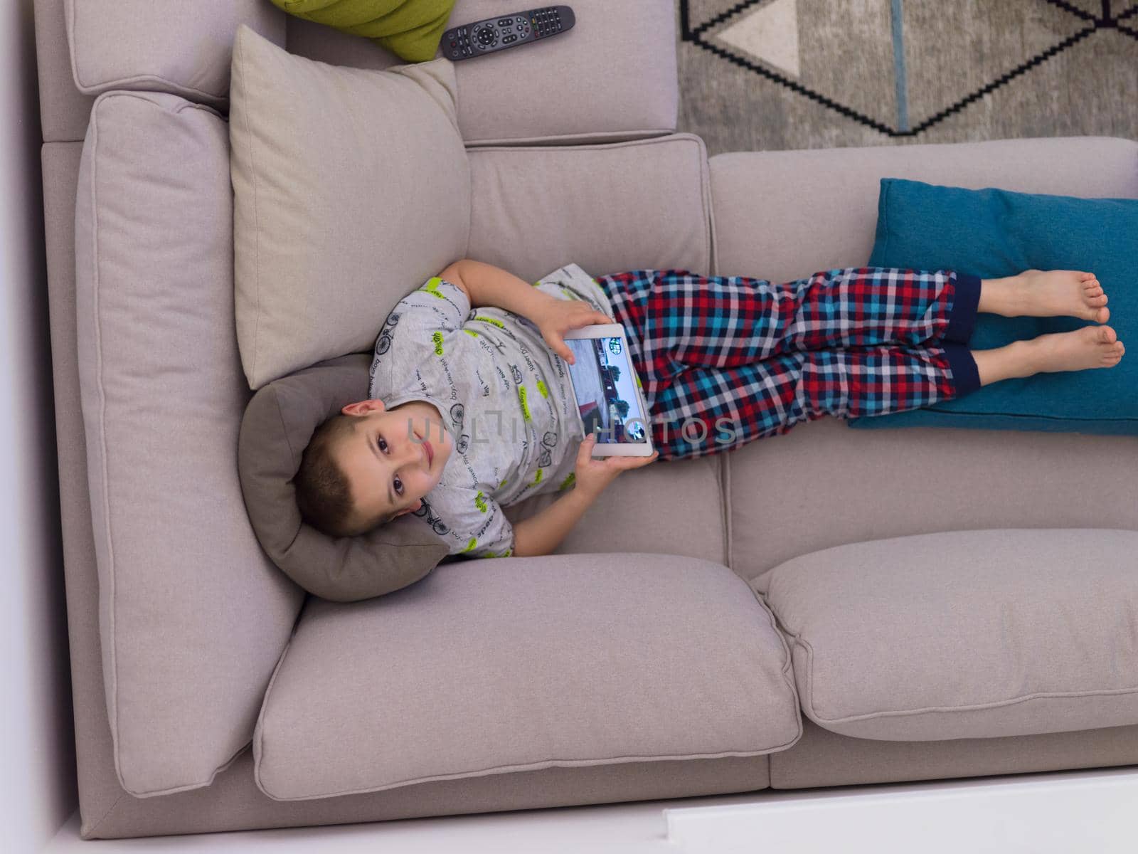 top view of little boy playing video games on tablet computer at home