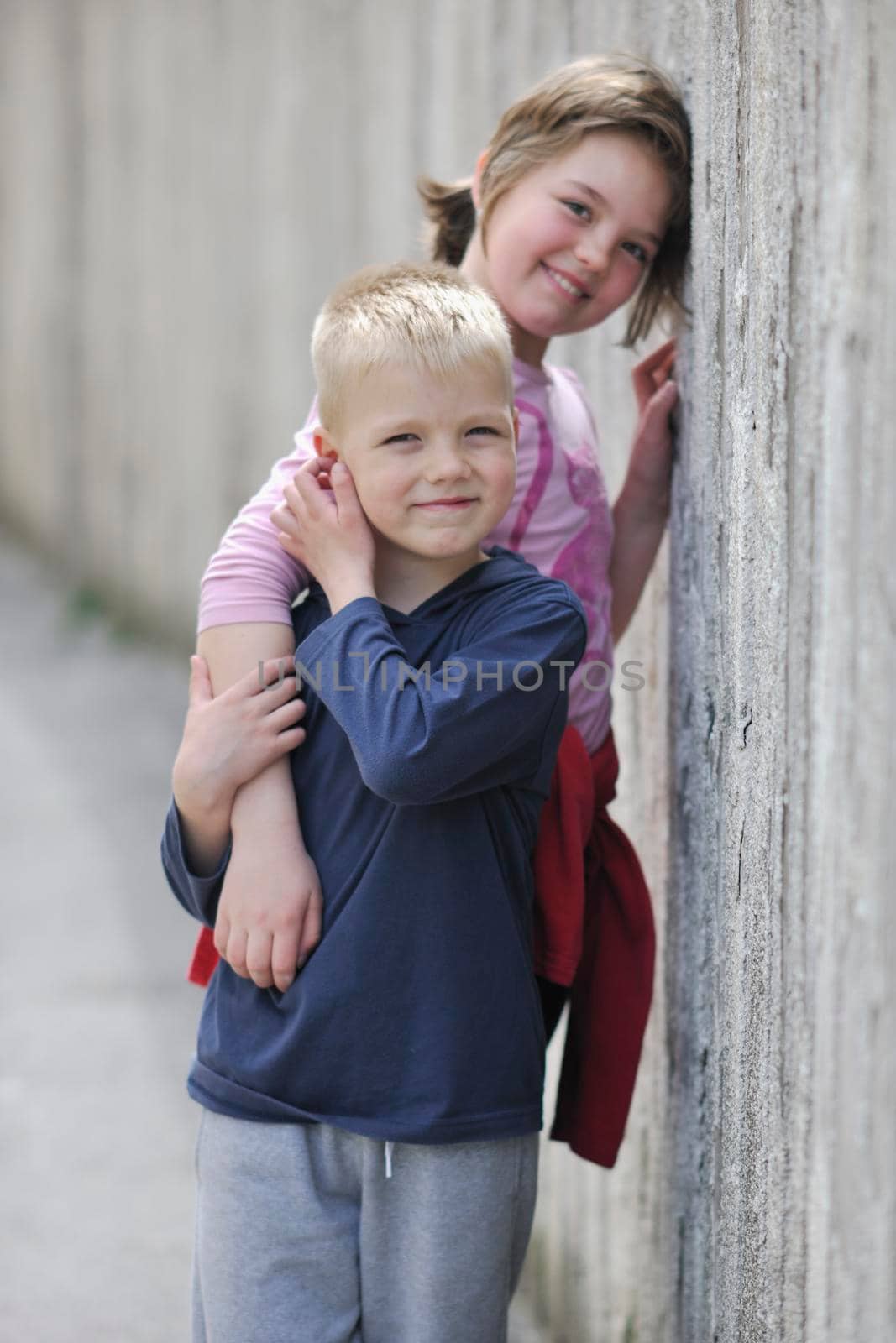 young boy and girl standing over iron fence at day and representing urban and fashion concept for child