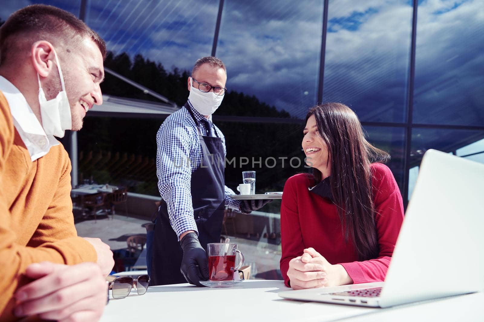 coronavirus outbreak Group of casual business People in outdoor restaurant wearing protective medical mask, business team collaborating and brainstorming business ideas  while working on laptop