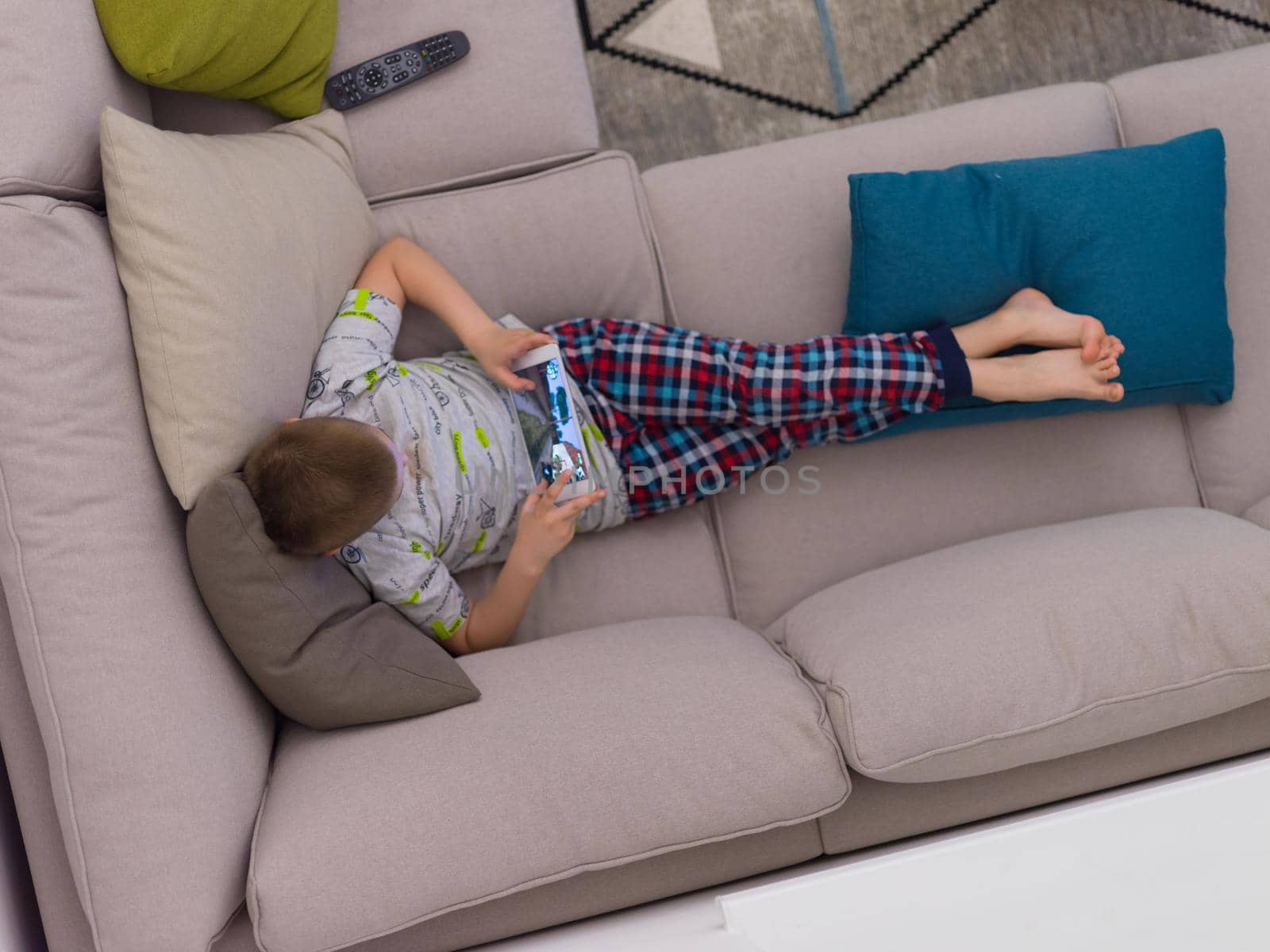 top view of little boy playing video games on tablet computer at home