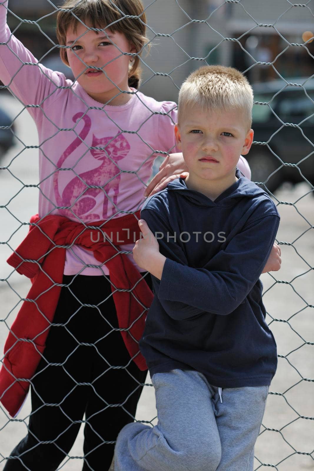 young boy and girl standing over iron fence at day and representing urban and fashion concept for child