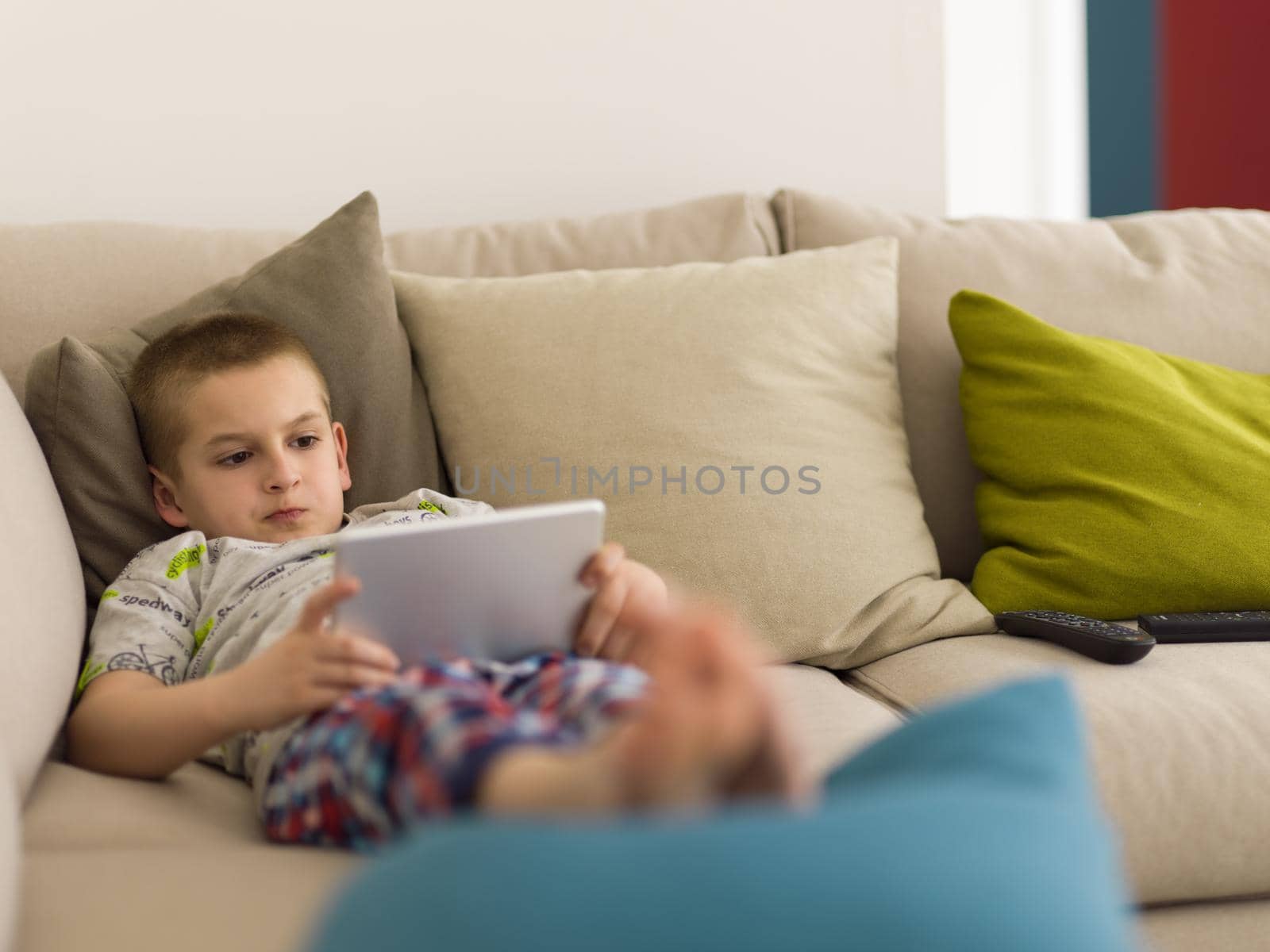 little boy playing video games on tablet computer at home