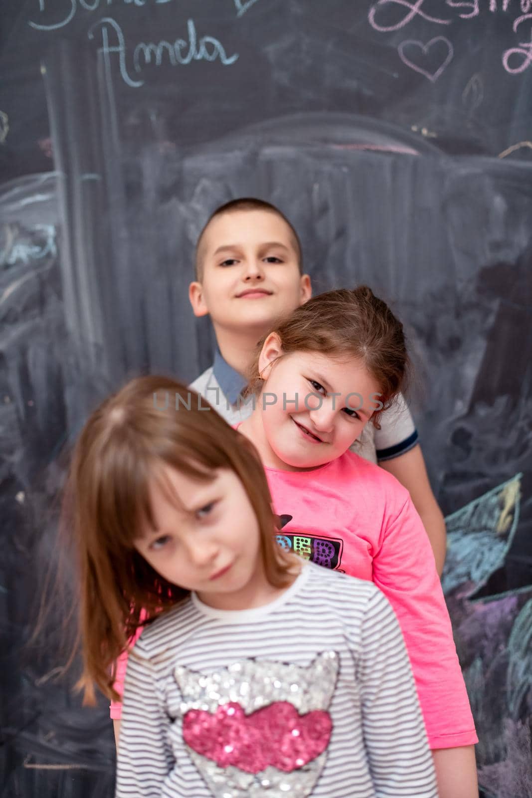 group portrait of happy childrens standing one behind the other while having fun in front of black chalkboard