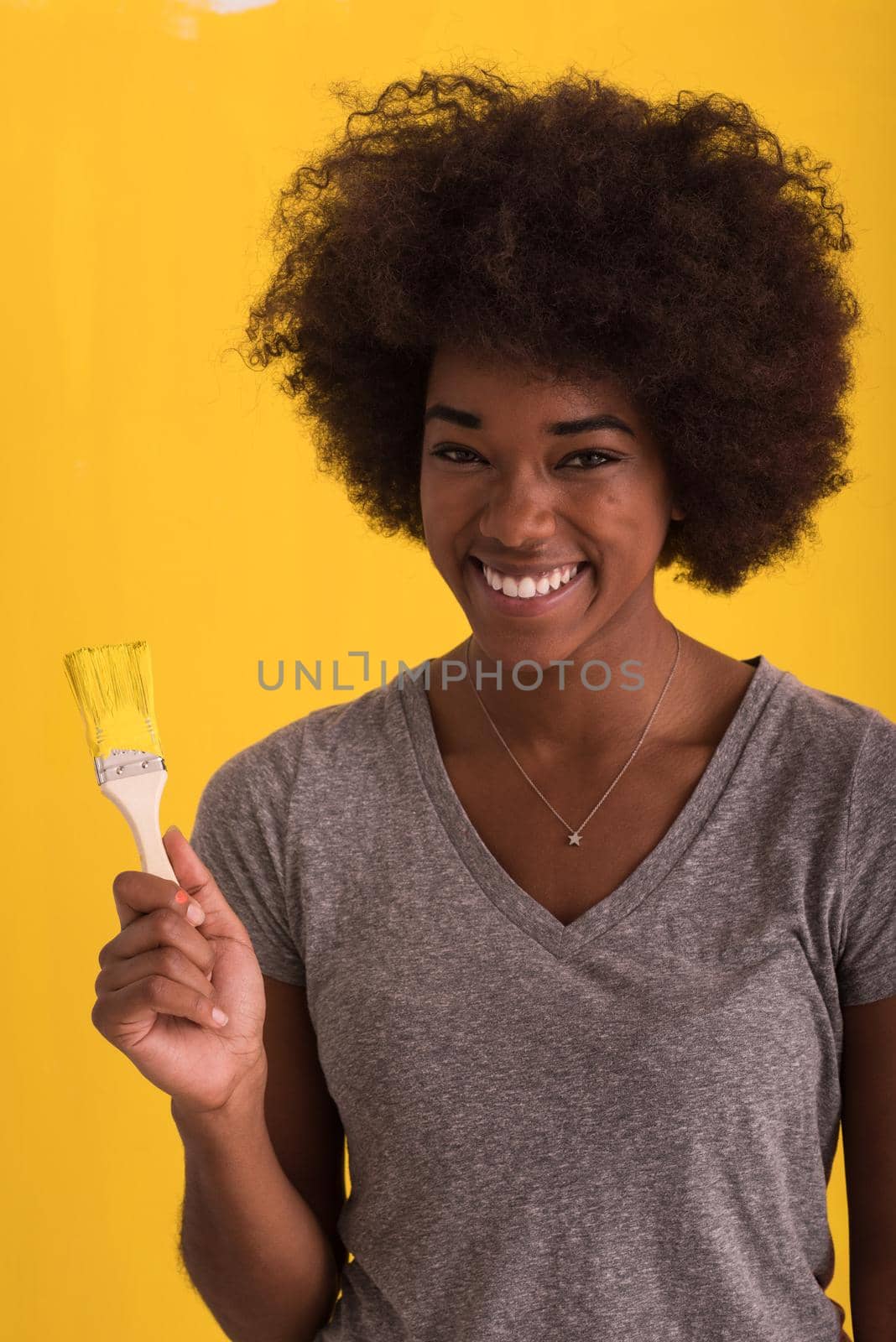 portrait of a young beautiful African American woman painting wall in her new apartment