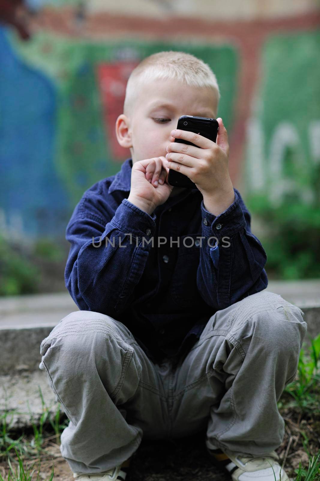 young blonde boy playing videogames outdoor in park