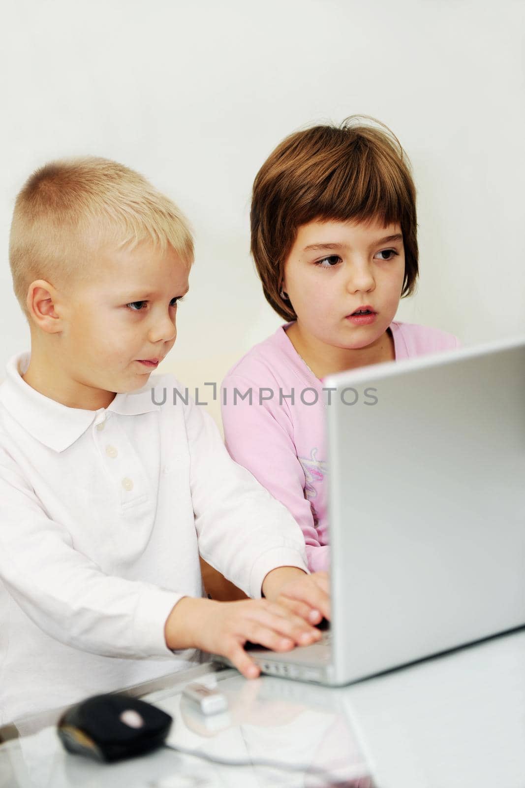two happy children playing games and learnig education lessons on laptop computer at home