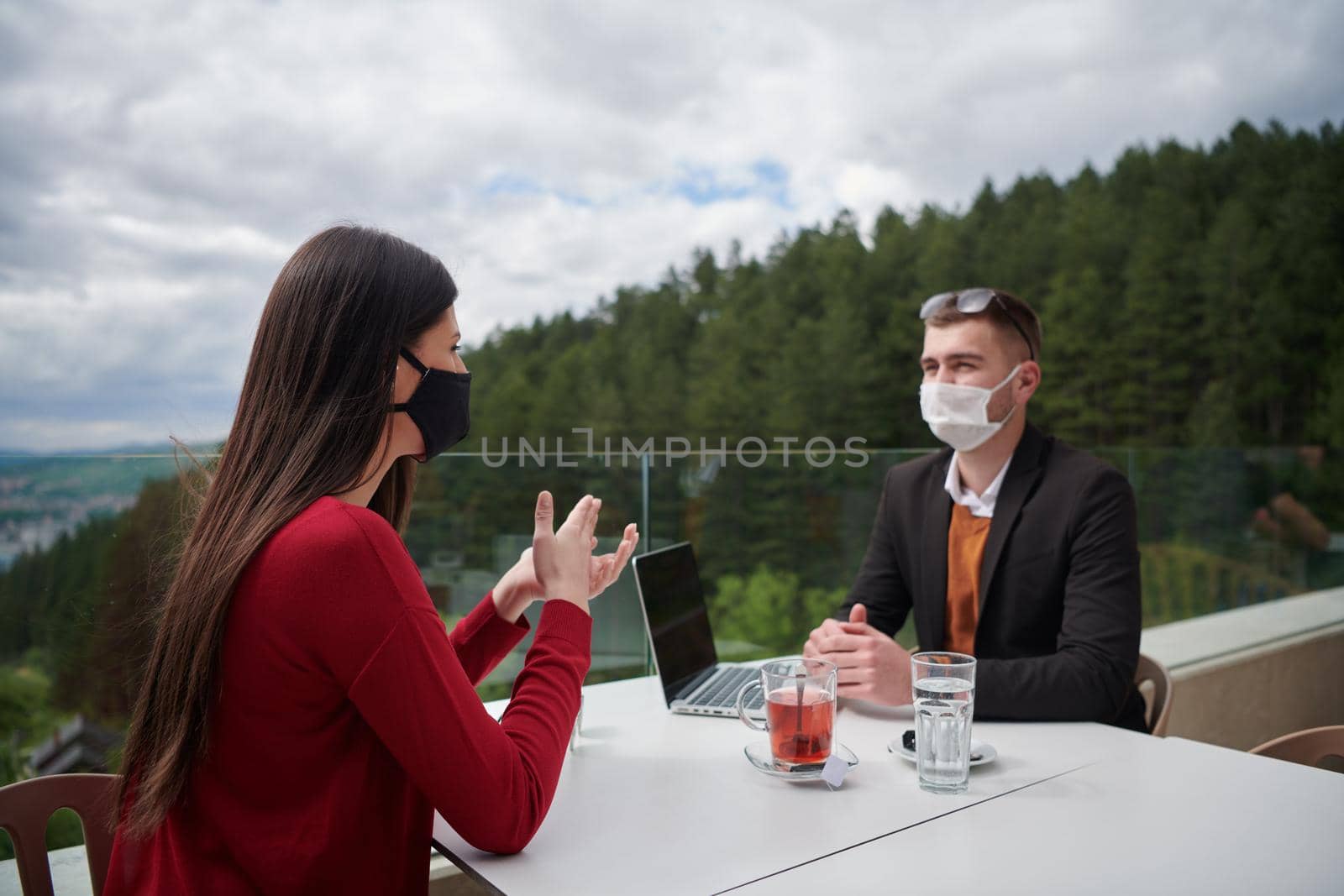 coronavirus outbreak Group of casual business People in outdoor restaurant wearing protective medical mask, business team collaborating and brainstorming business ideas  while working on laptop