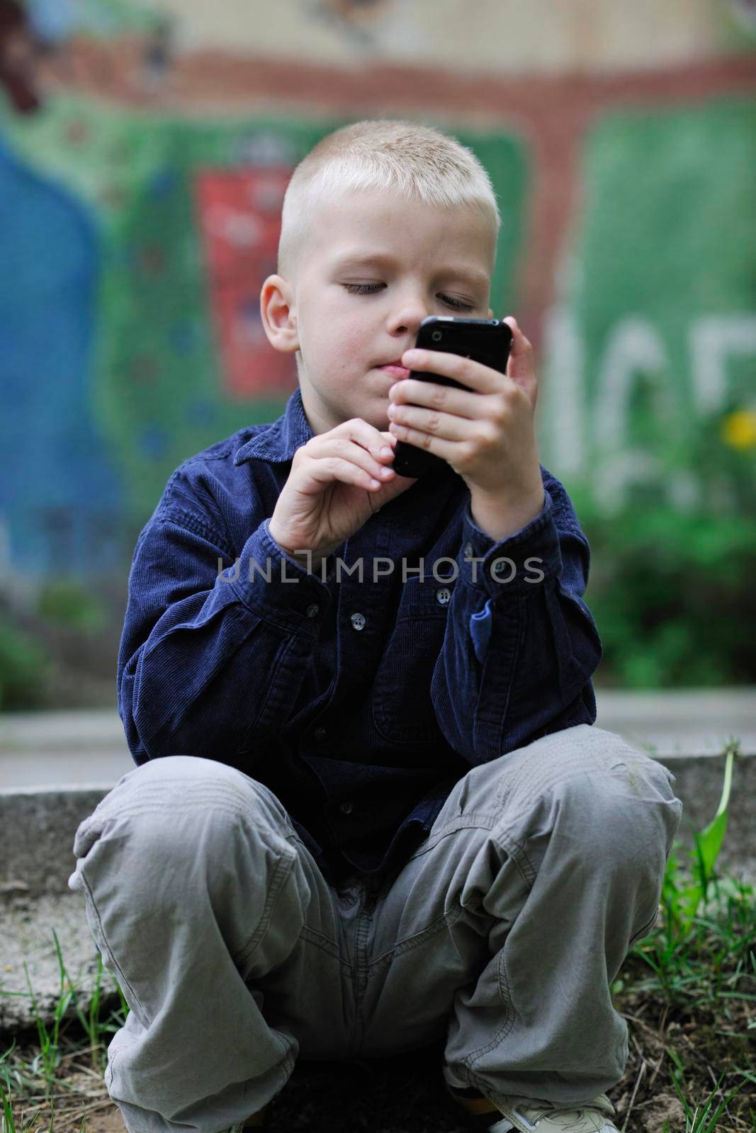 young blonde boy playing videogames outdoor in park