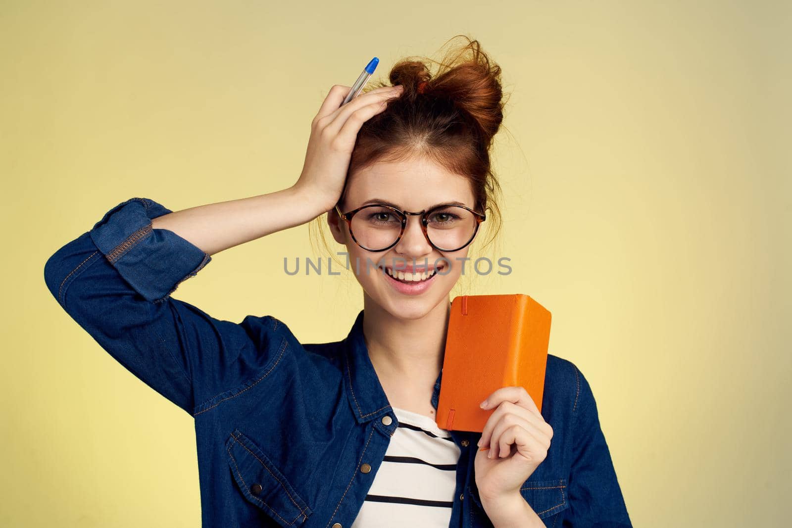 woman student with glasses notepad with pen yellow background. High quality photo
