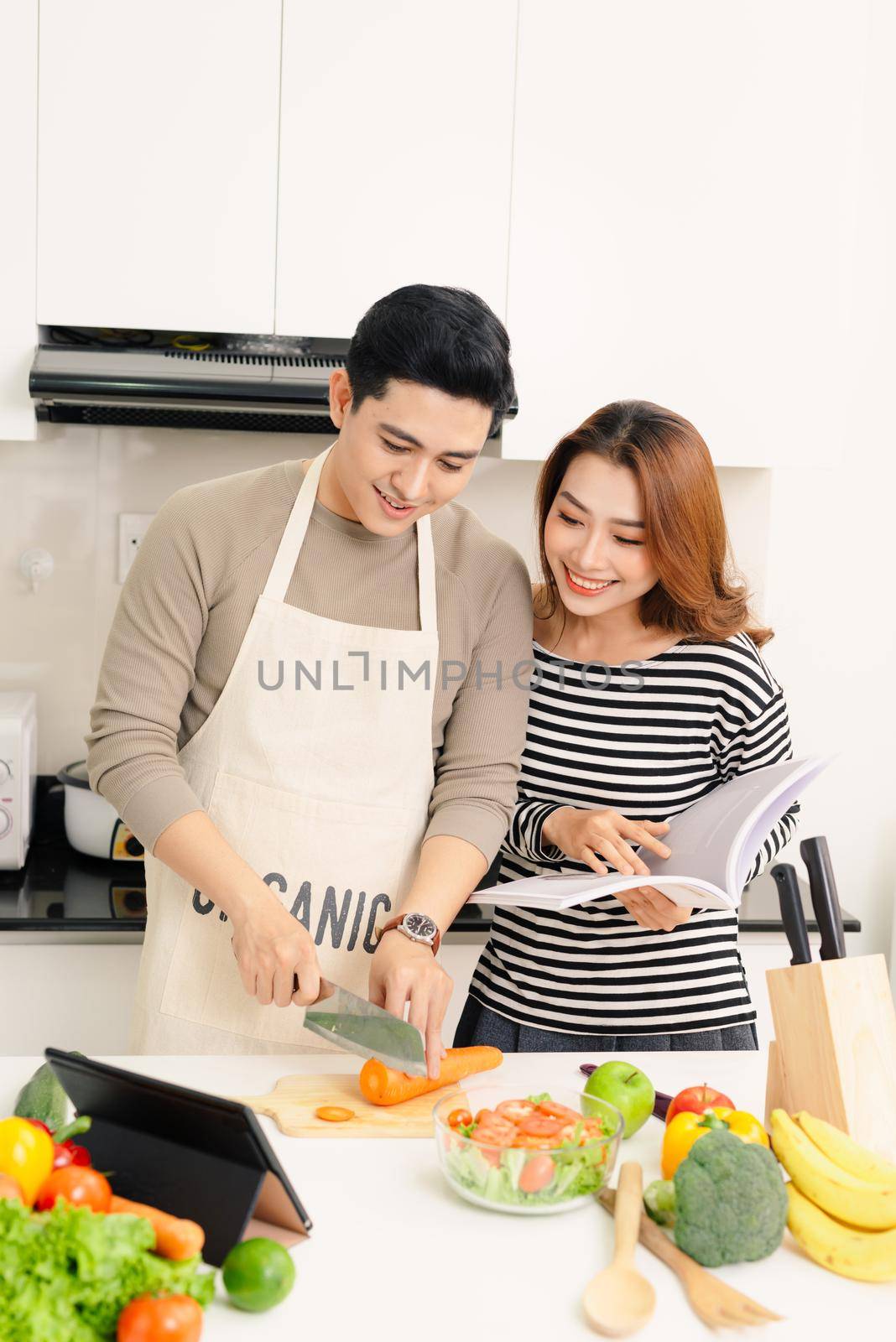 Happy couple is preparing healthy food on light kitchen