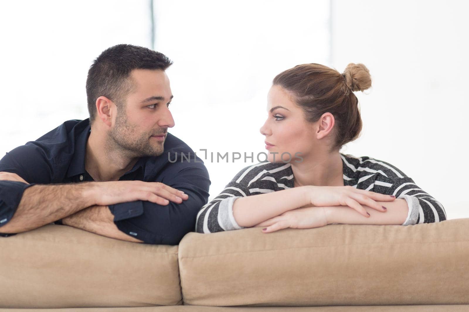 Portrait of young couple sitting on sofa in modern white apartment