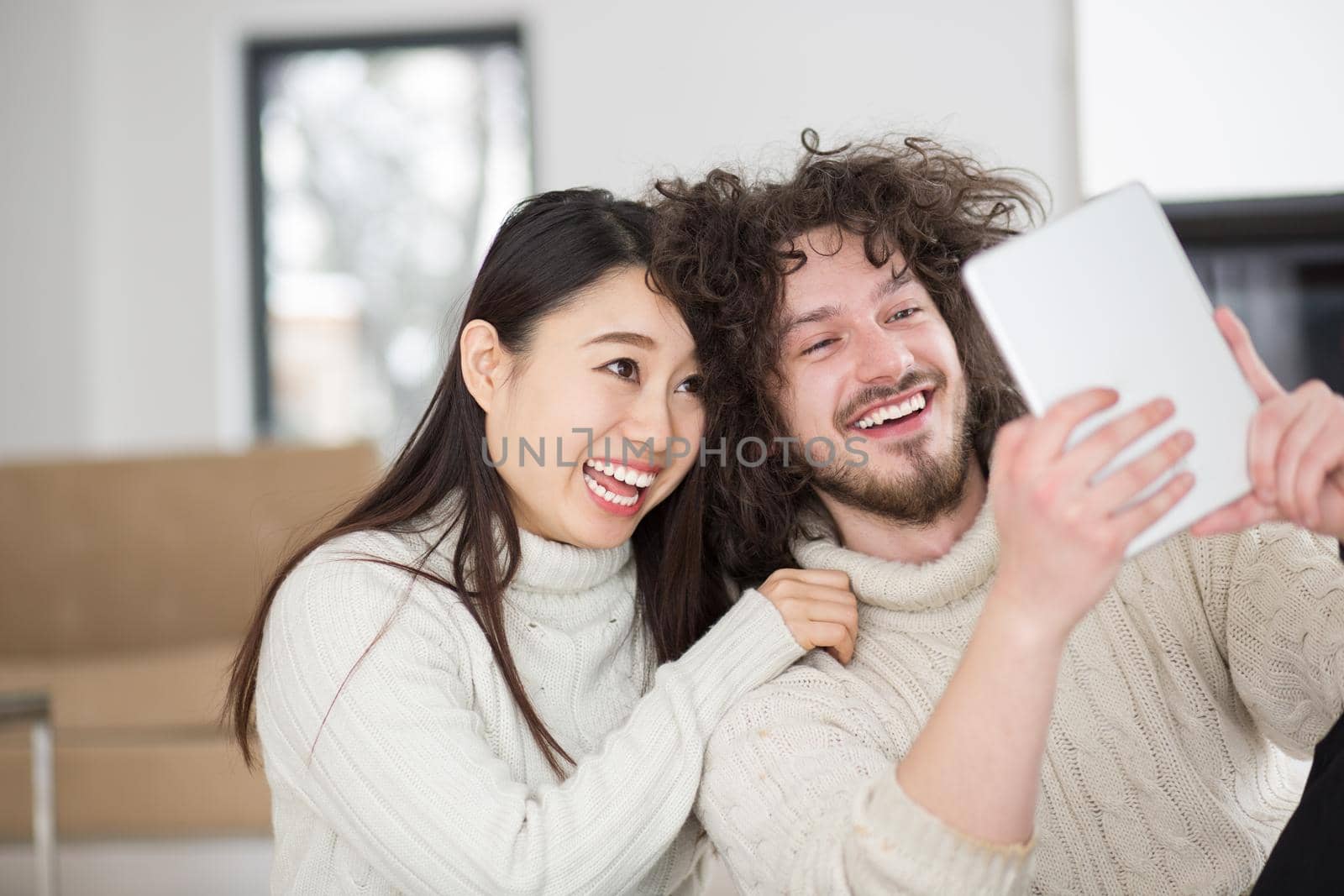 multiethnic couple using tablet computer in front of fireplace by dotshock