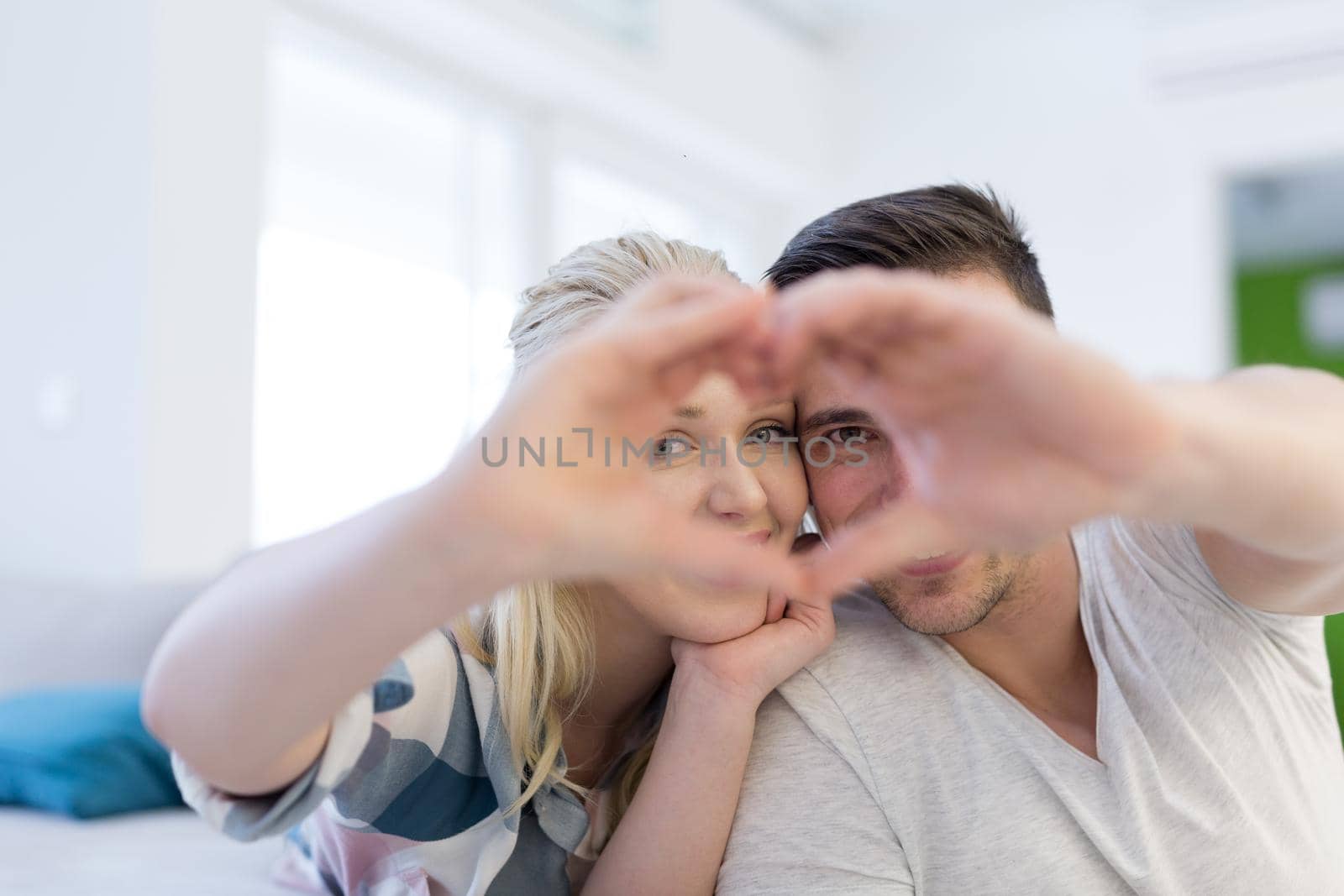 Young lovely couple making heart with hands at home