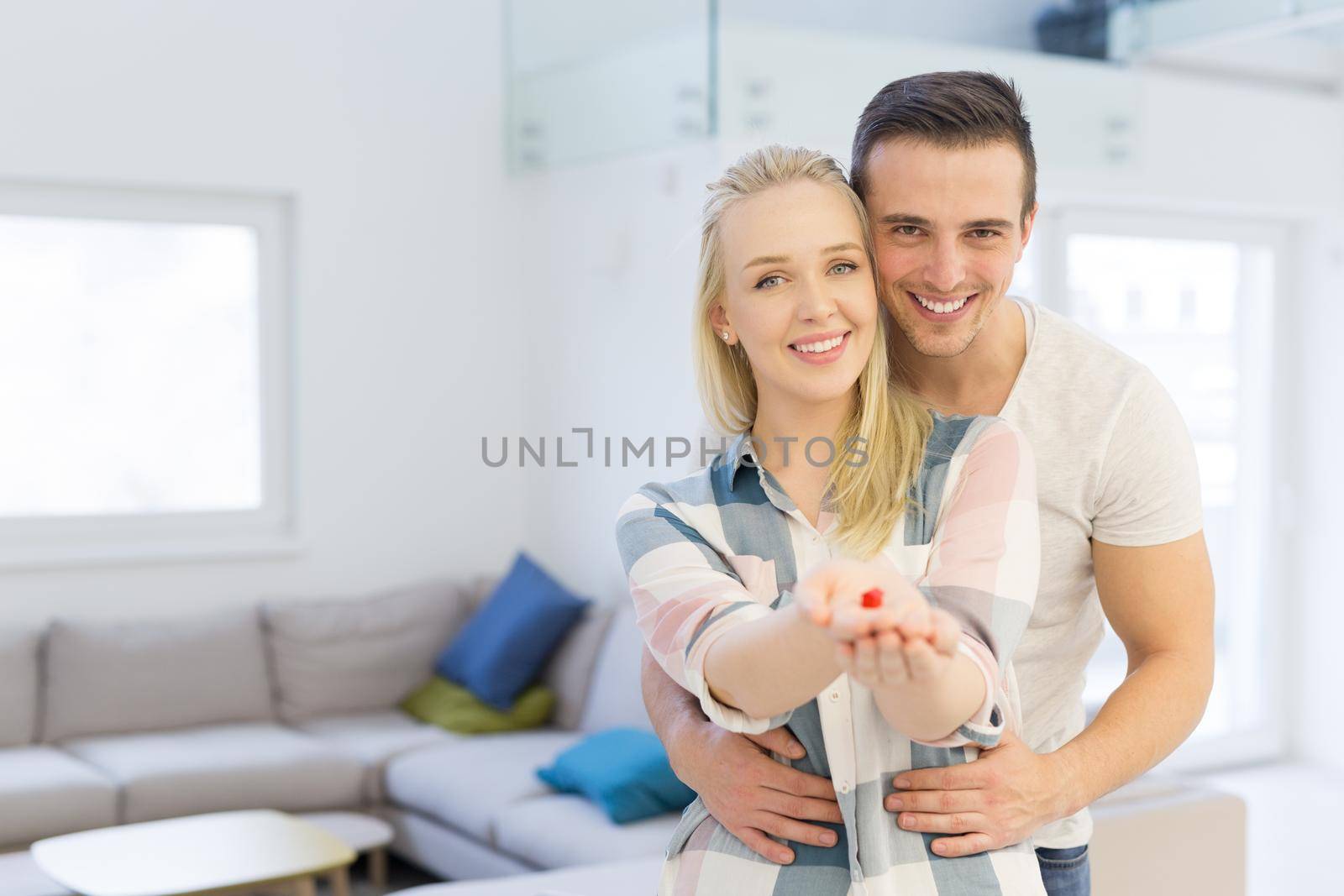 Happy couple hugging and showing small red house in hands Concept of buying house to start a family