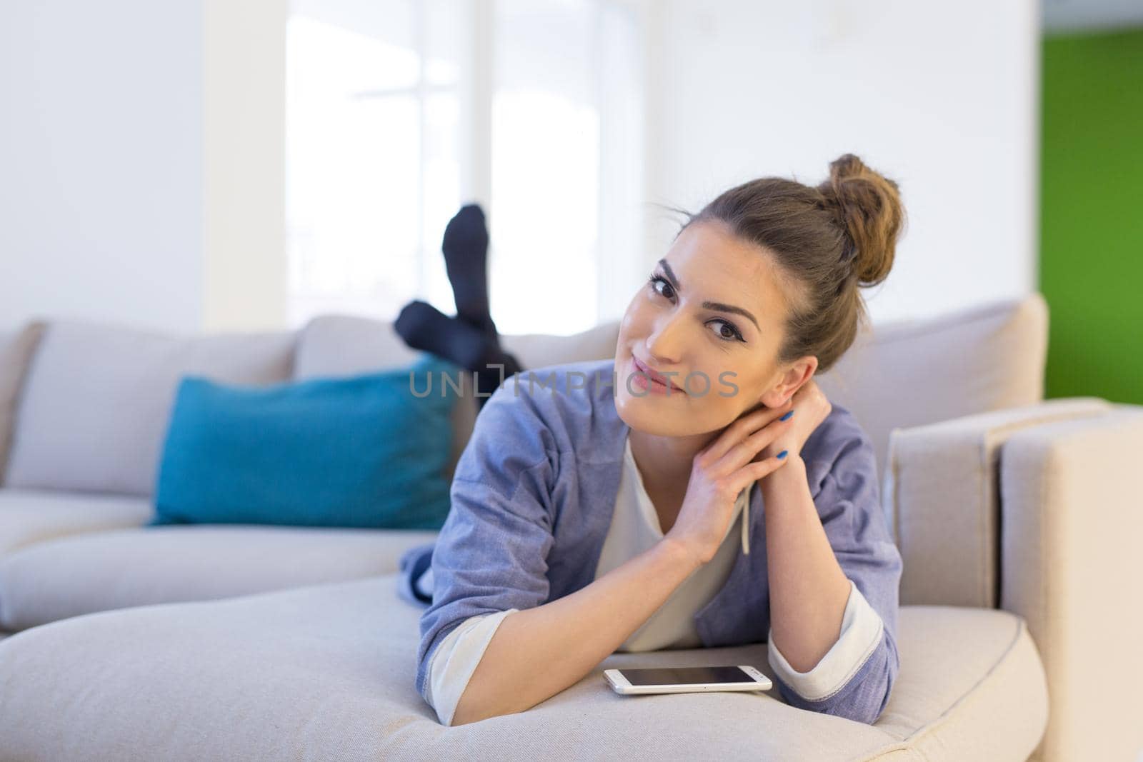 young happy woman using mobile phone on sofa at luxury home